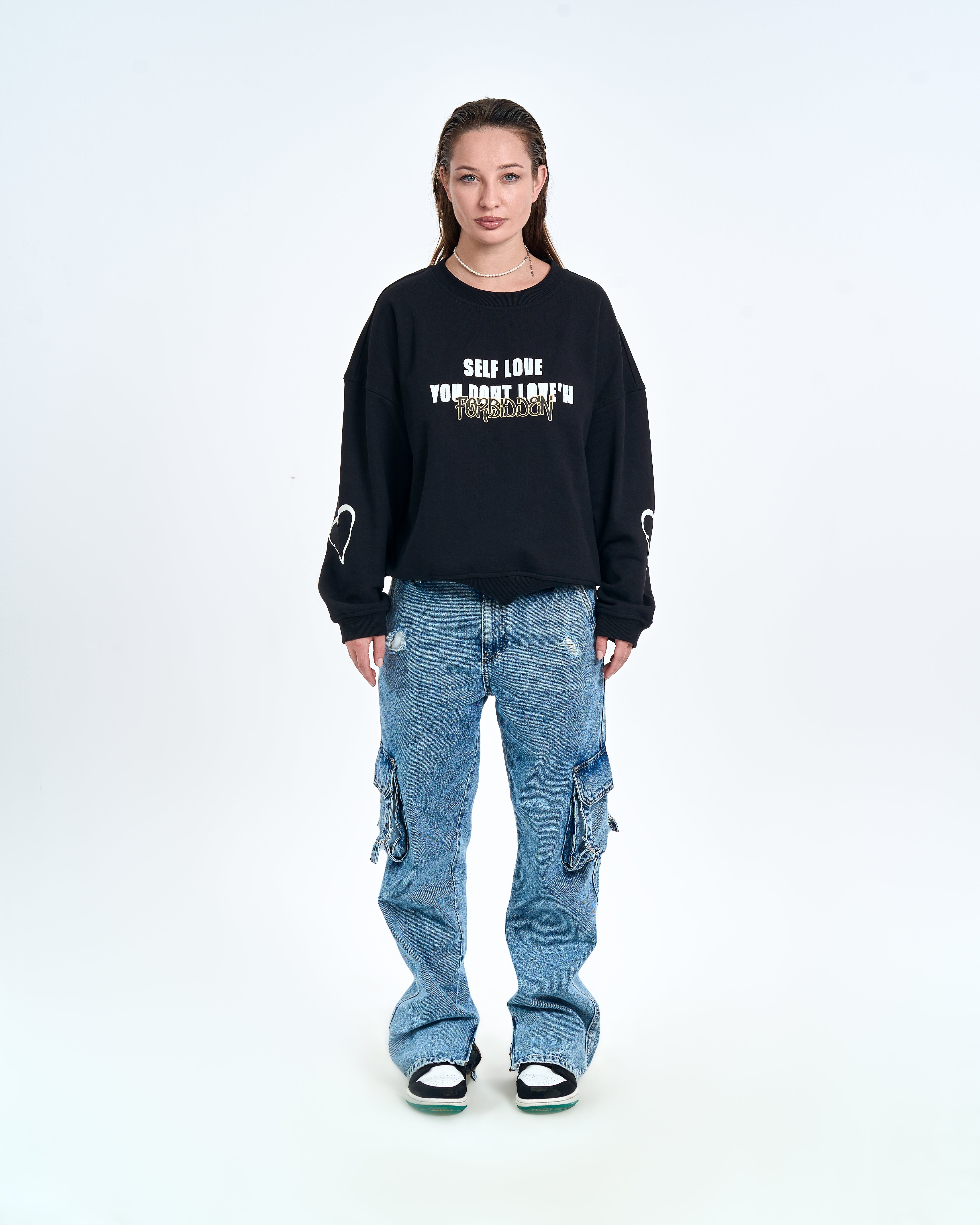 MOE CHARLIE Forbidden Sweater Schwarz - Frontansicht Damen, Statement-Print und Herz-Ärmel, blaue Cargo-Jeans