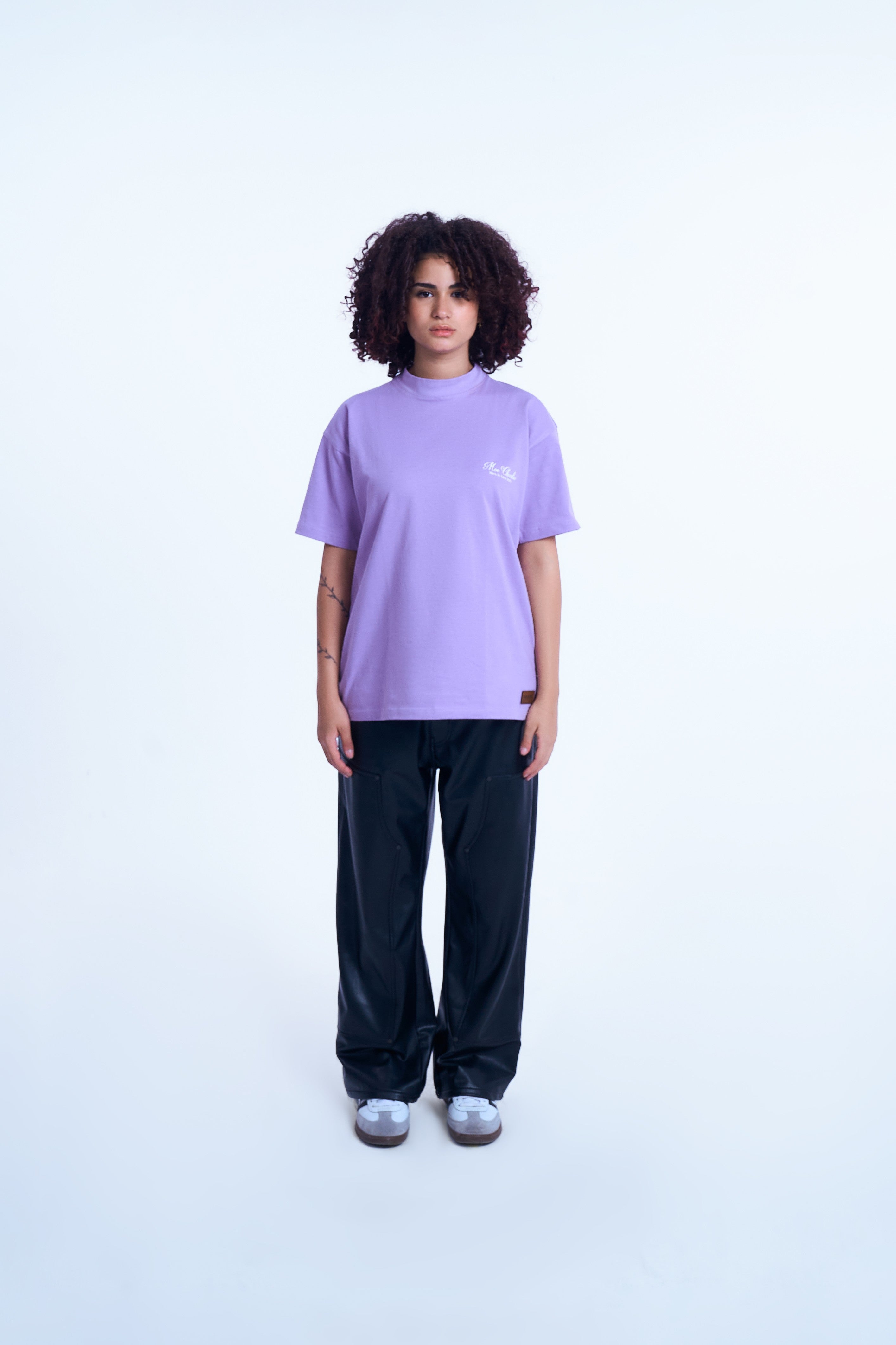 MOE CHARLIE Basic T-Shirt in Lavendel mit Script-Logo, Lederpatch - weibliches Model mit schwarzer Leder-Pants
