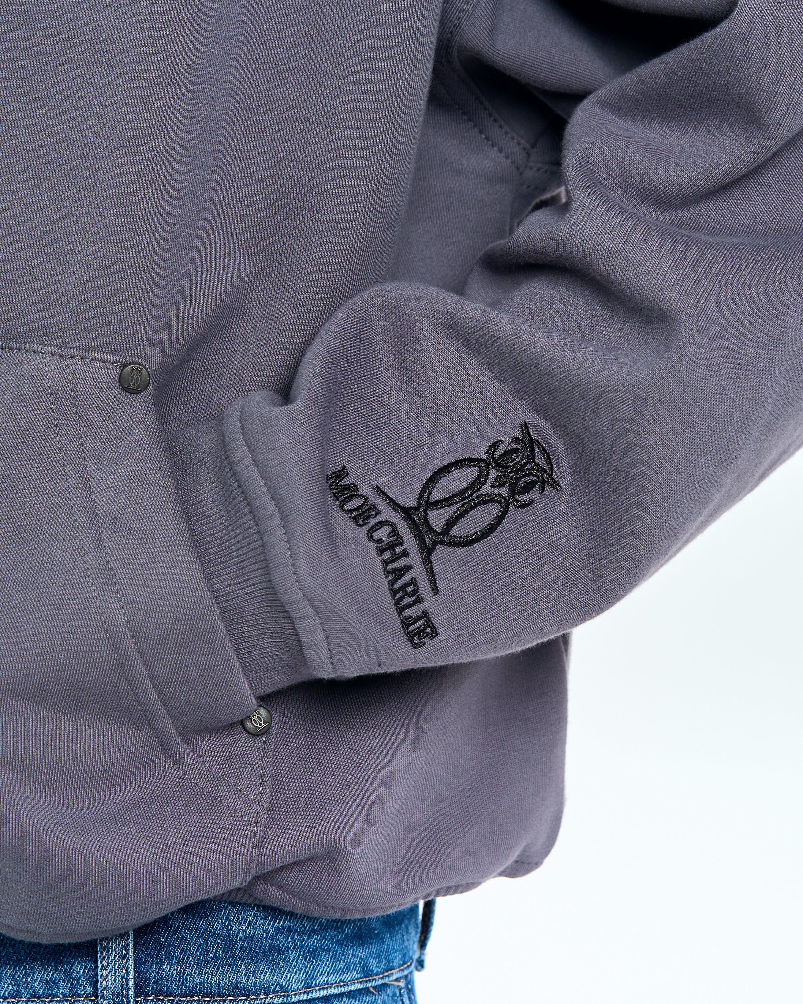 Aermeldetail Born in Exile Hoodie MOE CHARLIE - gesticktes Owl-Crest am grauen Buendchen in Nahaufnahme