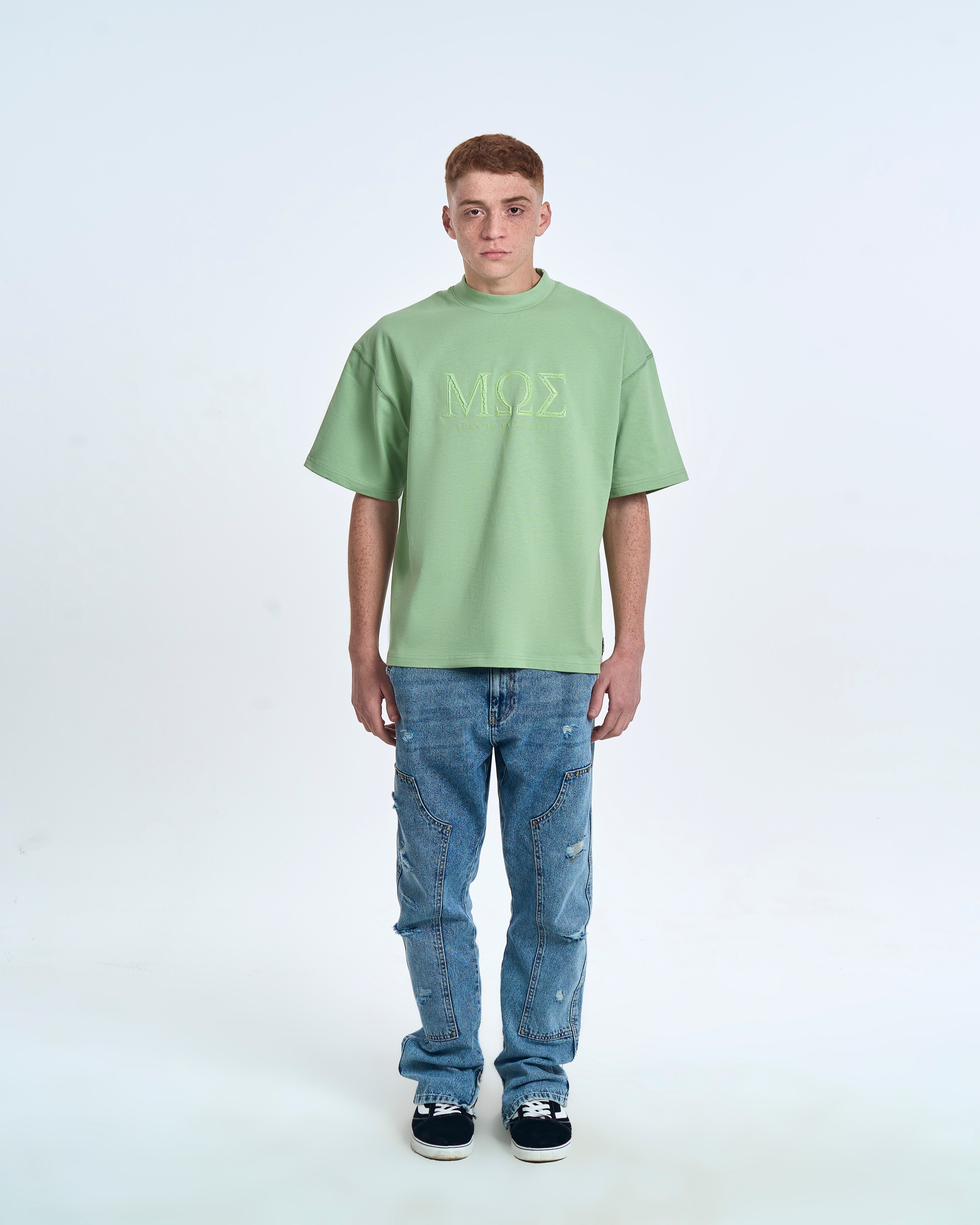 MOE CHARLIE Born In Exile T-Shirt Mintgrün – Frontansicht Herrenmodel, MΩΣ-3D-Print, blaue Carpenter-Jeans