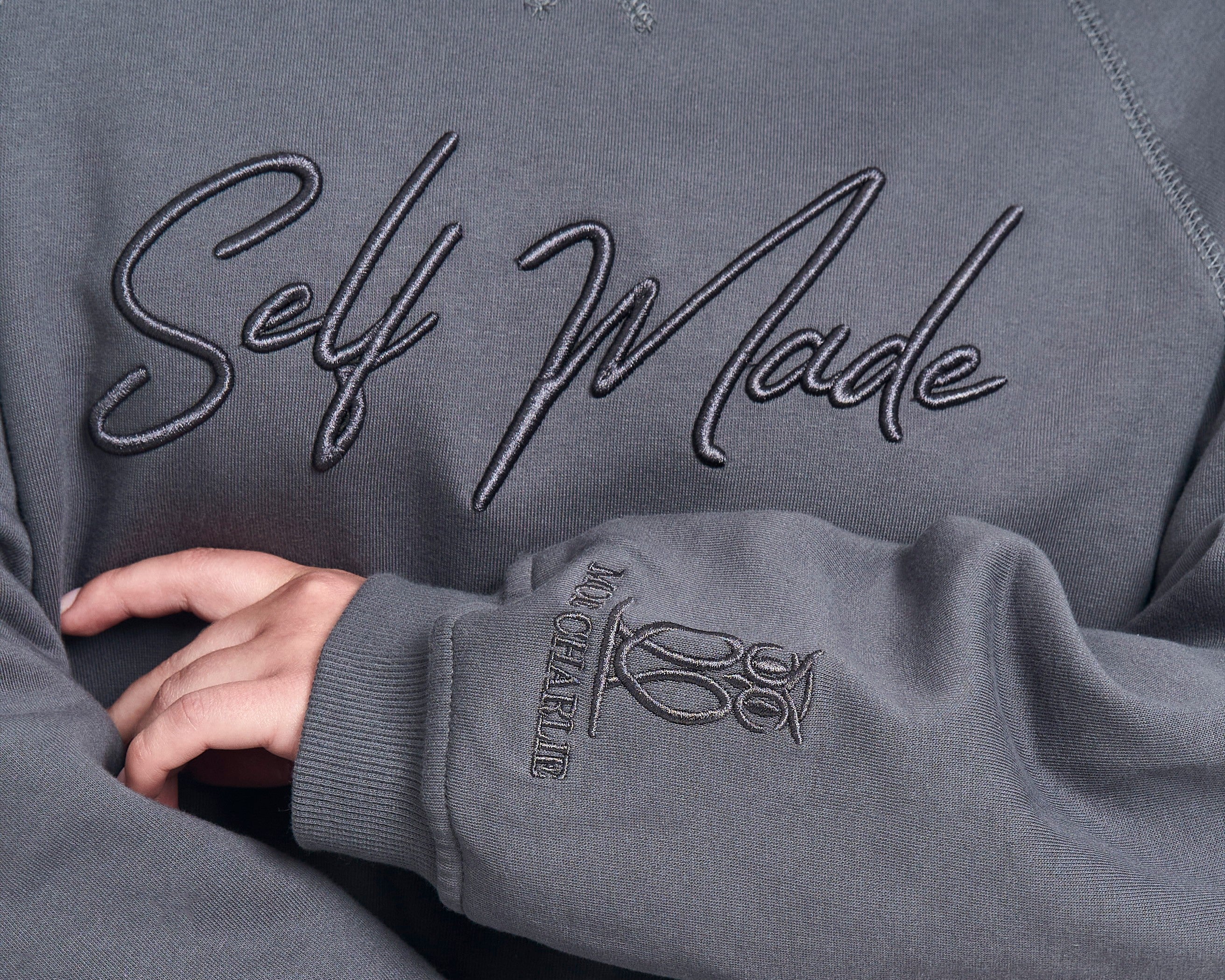 Nahaufnahme Self-Made-Stickerei auf grauem MOE CHARLIE Hoodie mit Markensignet am Ärmelabschluss