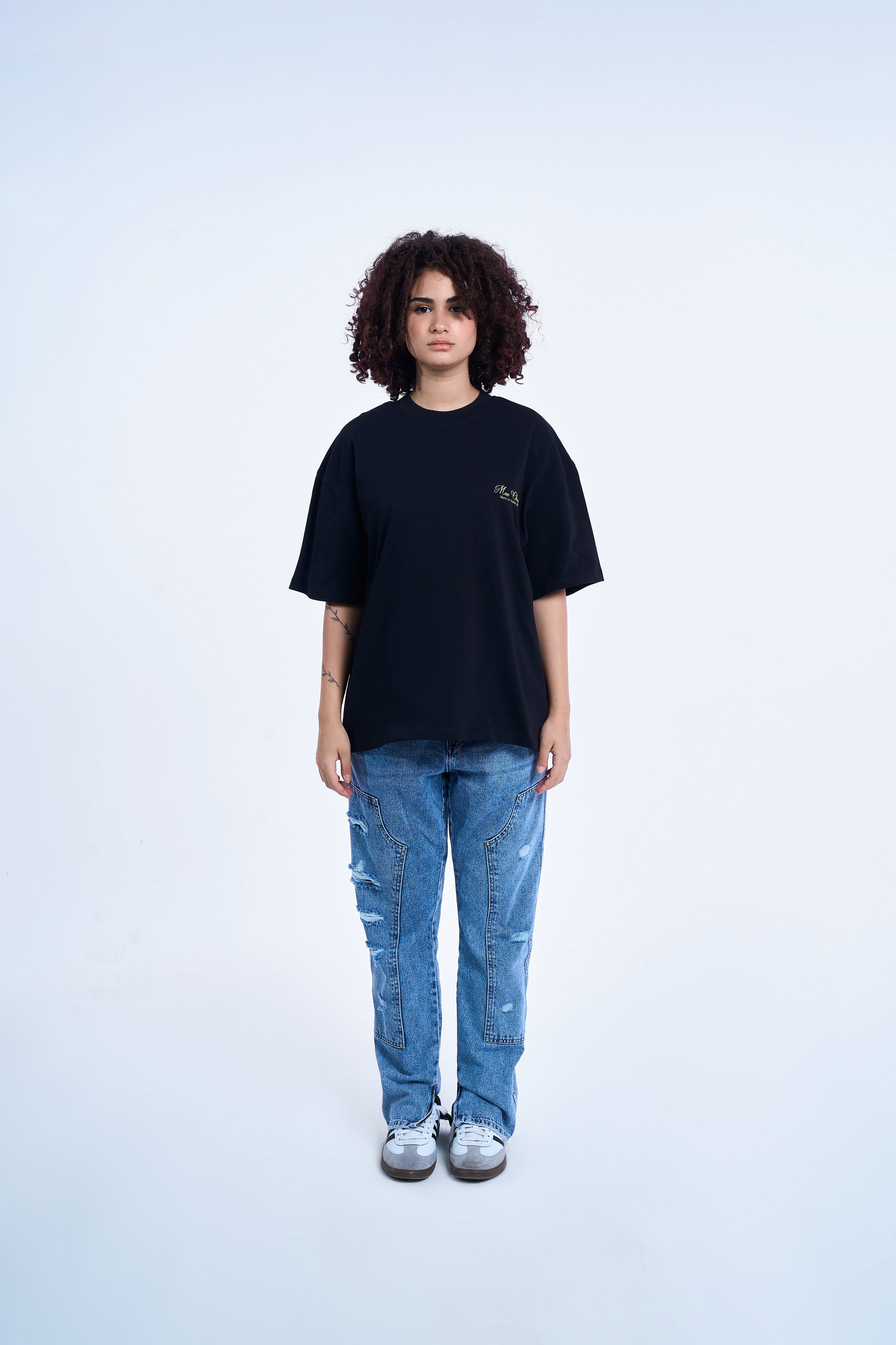MOE CHARLIE Ready To Die Shirt weibliches Model front – Oversize schwarz, Brustlogo gold, Carpenter Flare Jeans