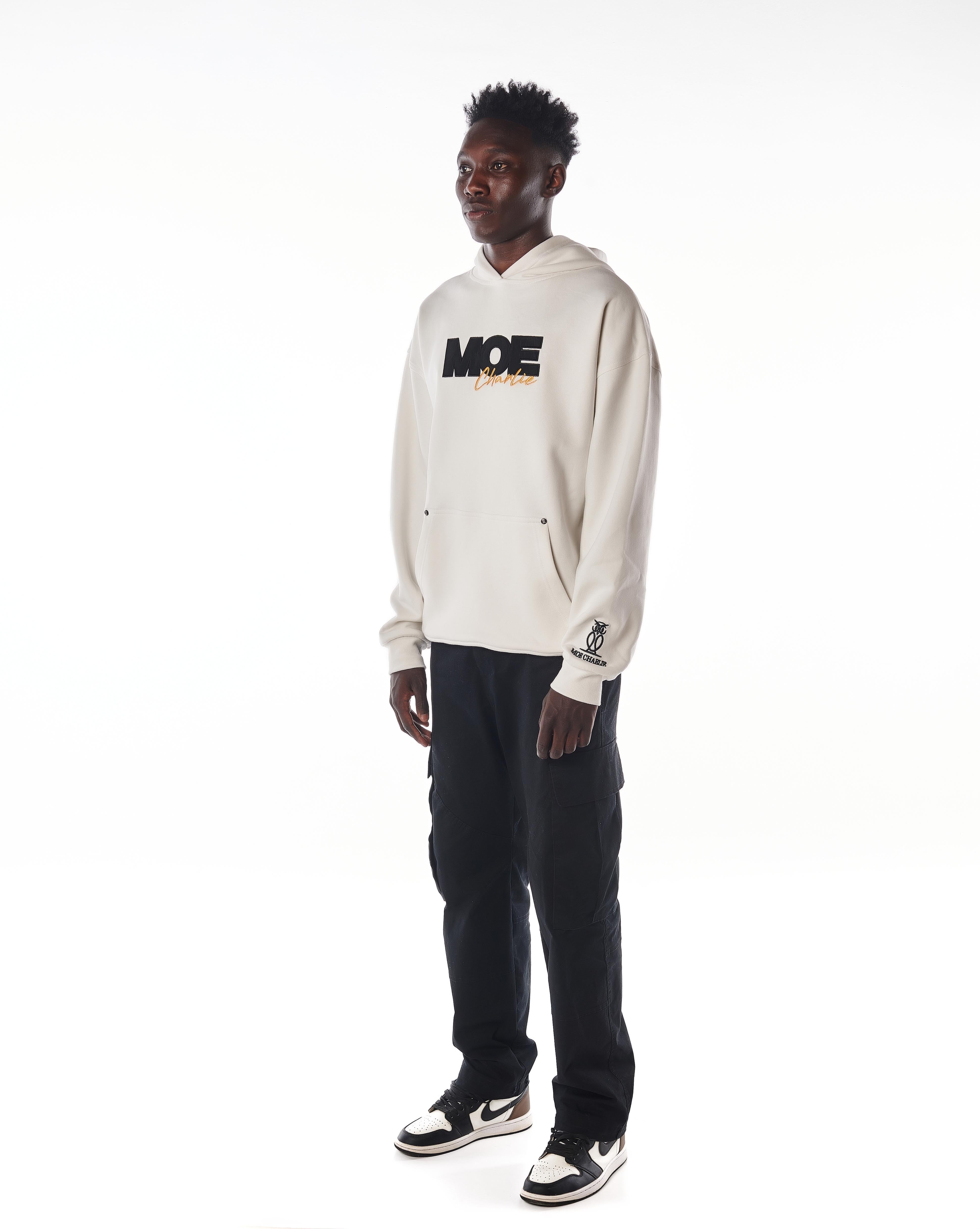 Seitenansicht links MOE CHARLIE Gold Passion Hoodie, Oversize-Silhouette, Frontprint und Ärmel-Logo erkennbar