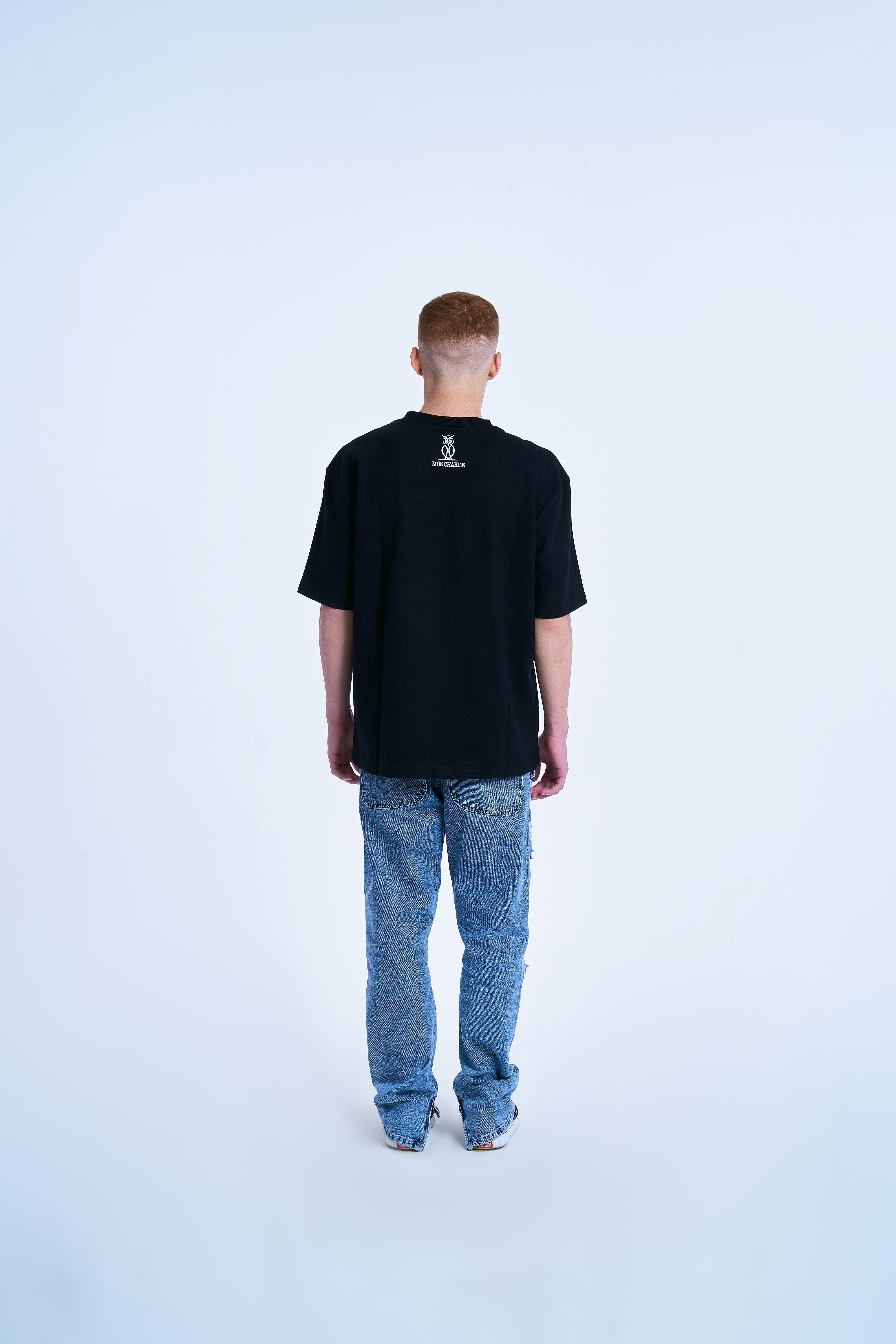 Rückenansicht Graffiti T-Shirt MOE CHARLIE in Schwarz, kleines Markenlogo auf dem Rücken, helle Jeans