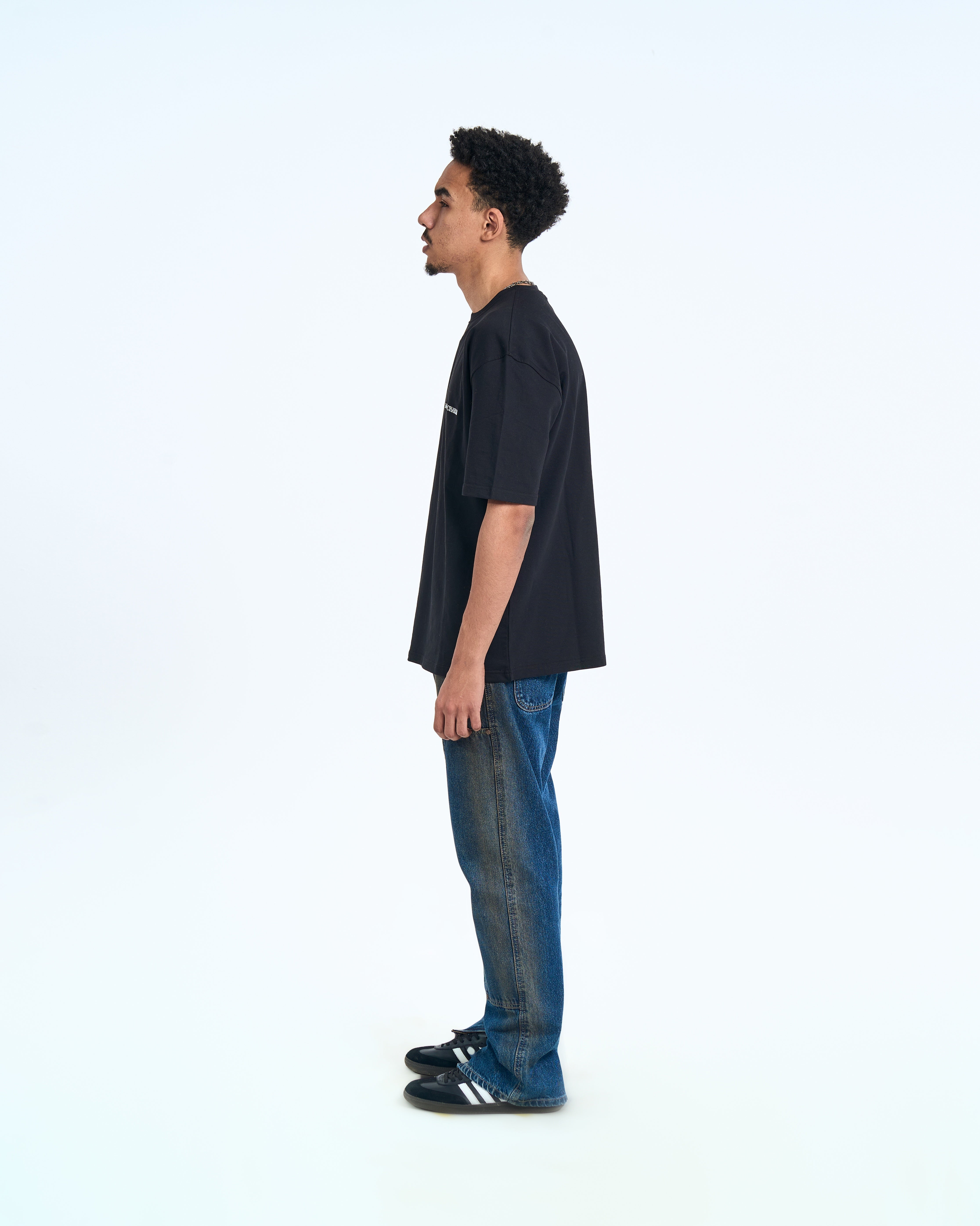 MOE CHARLIE Basic T-Shirt Schwarz – Seitenansicht links, Brust-Logo sichtbar, Herrenmodel mit Jeans und Sneaker