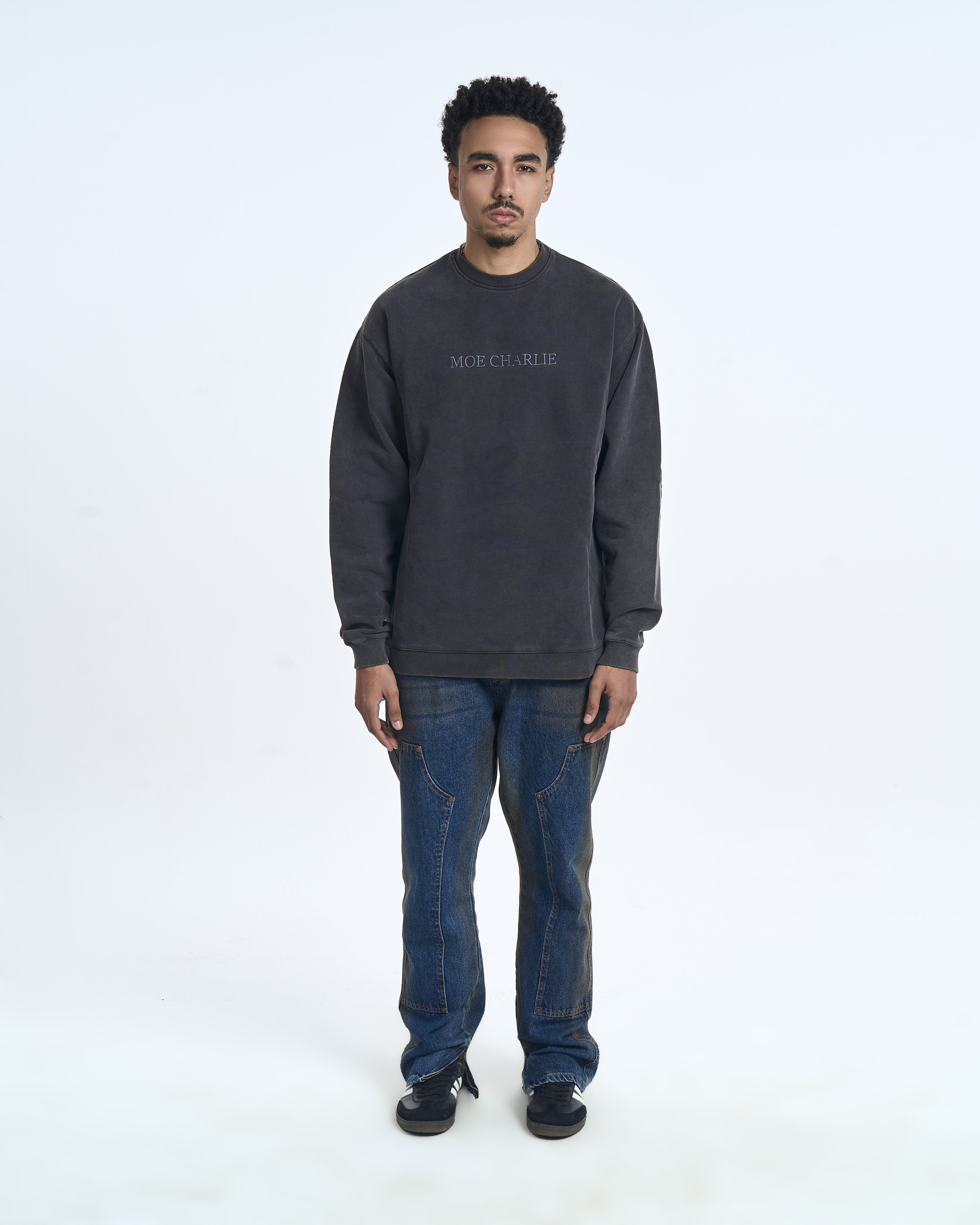 MOE CHARLIE Sweater Charcoal – Frontansicht Herrenmodel, ton-in-ton Brust-Logo, blaue Carpenter-Jeans