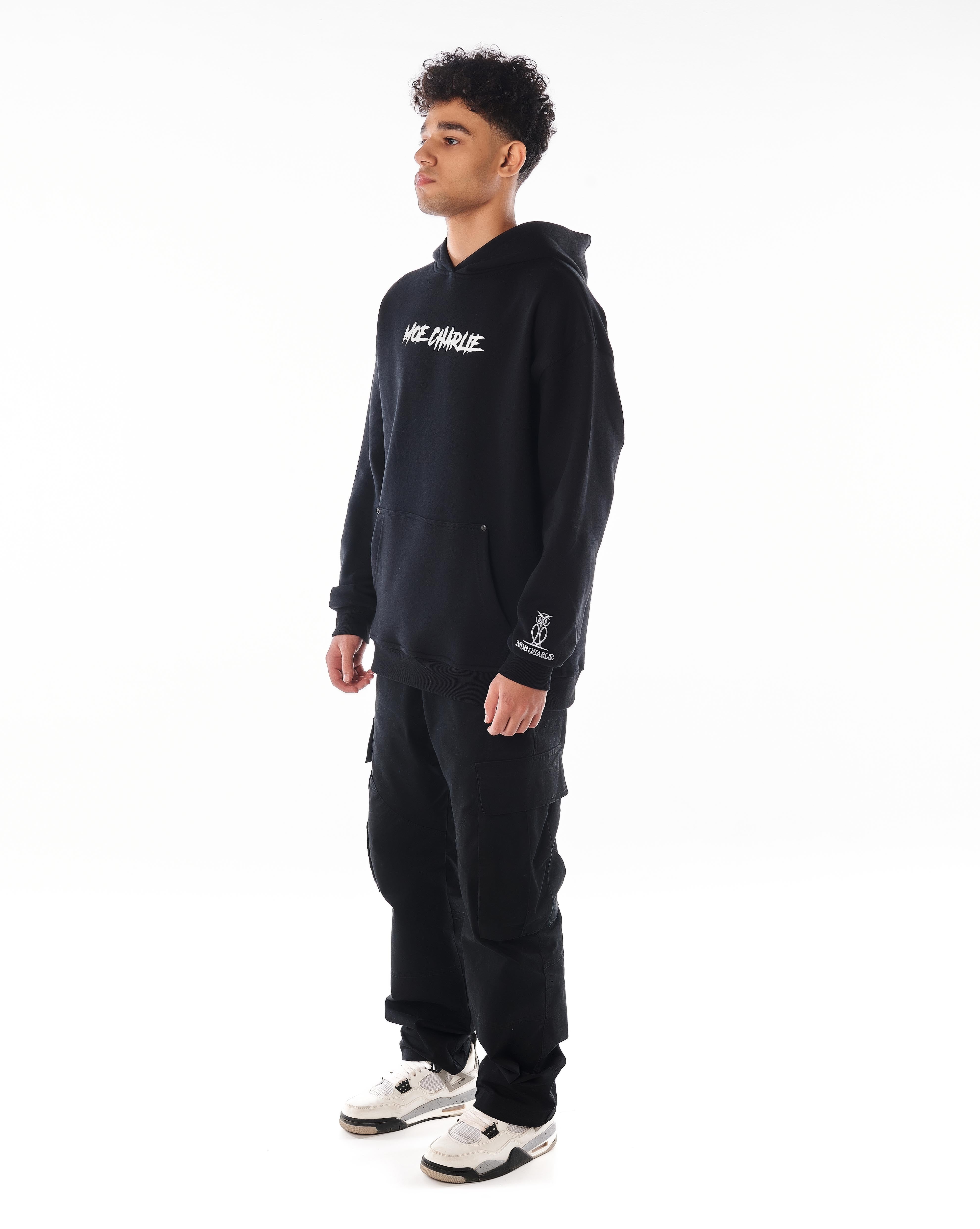Dreiviertelansicht MOE CHARLIE Predator Hoodie, Frontprint und Ärmel-Eulen-Logo sichtbar, Blick seitwärts