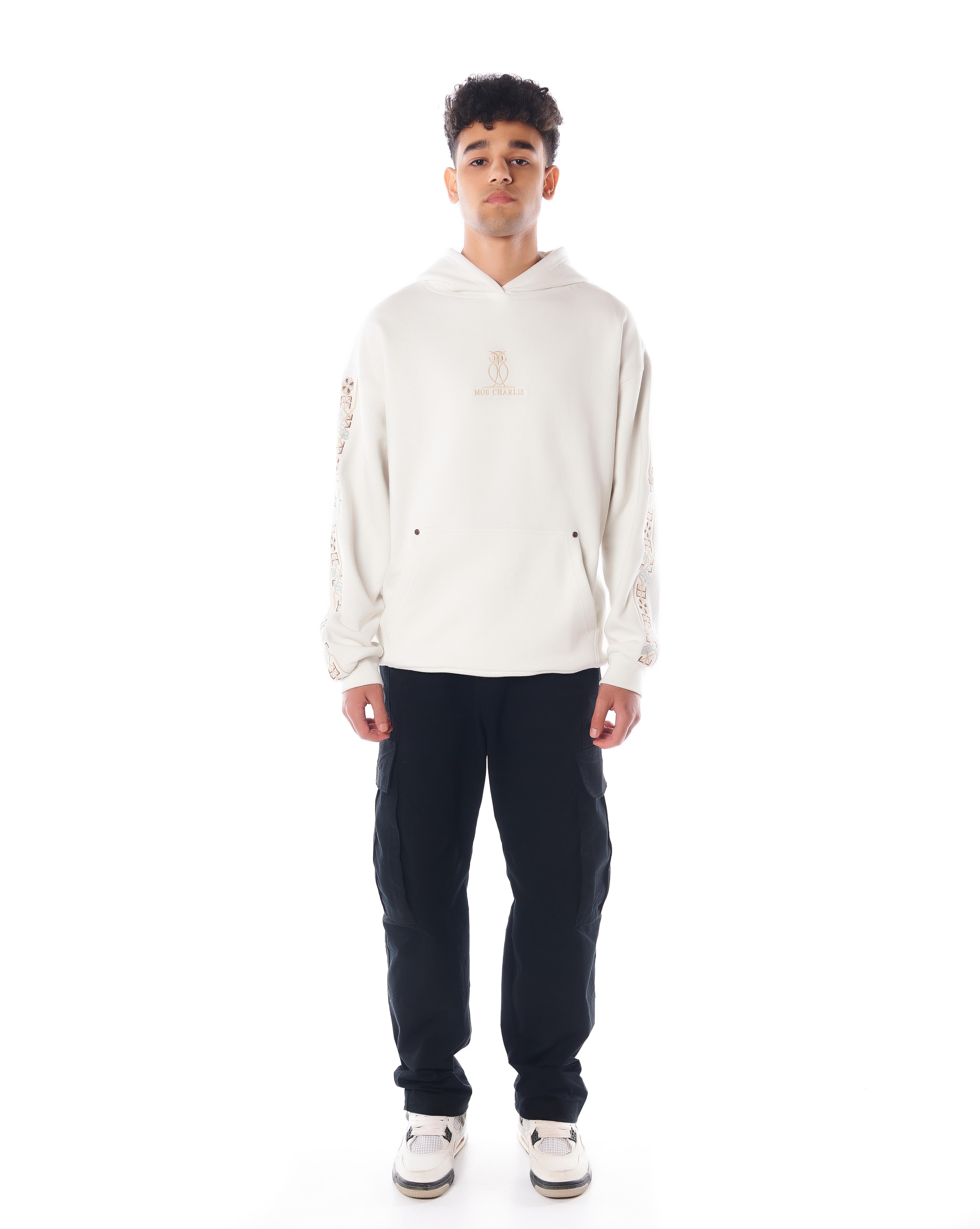 MOE CHARLIE The Culture Hoodie in Star White, Frontpose in Creme mit goldener Owl-Stickerei und floraler Ärmelstickerei