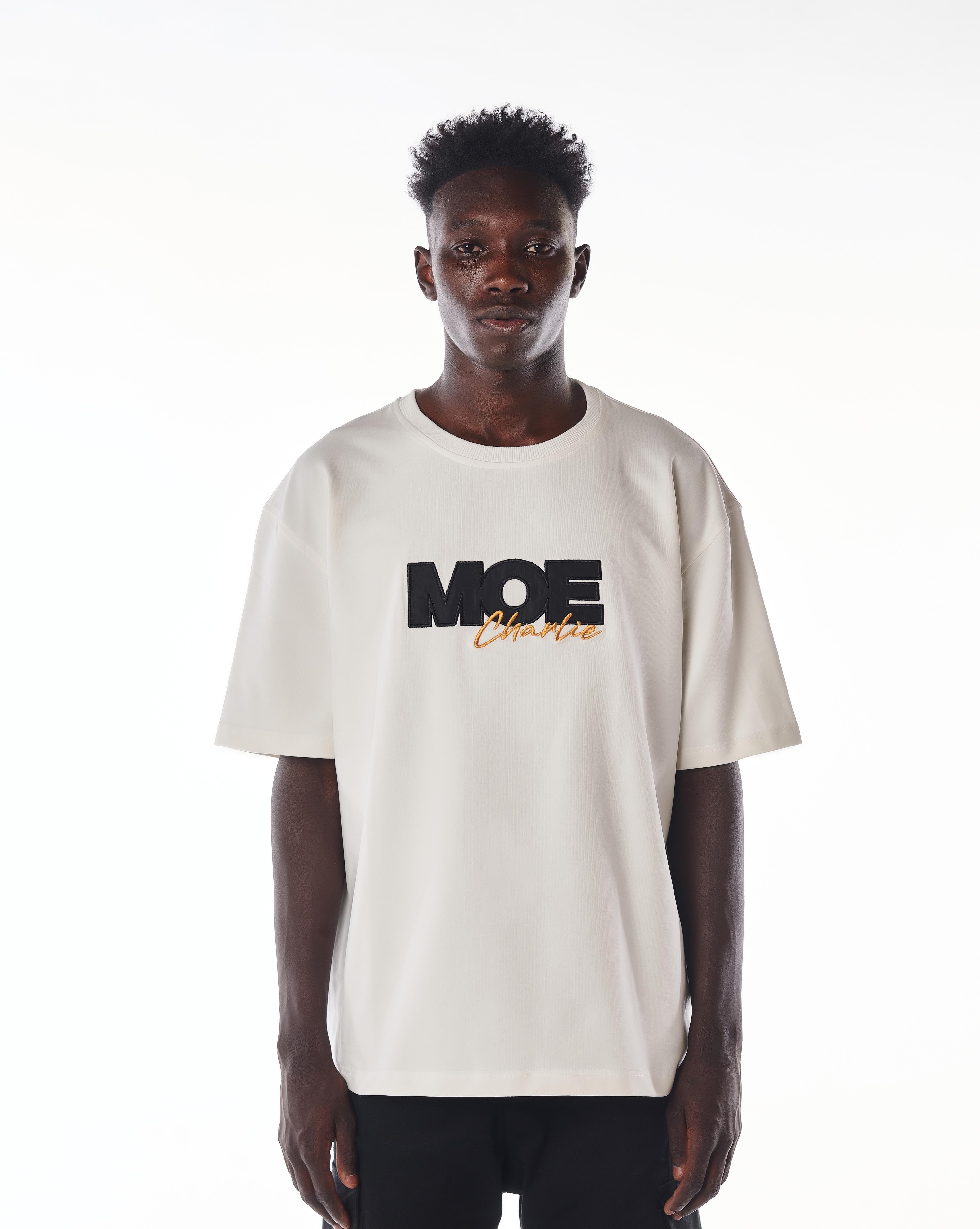 Nahaufnahme Frontprint MOE CHARLIE Gold Passion T-Shirt, schwarze MOE-Buchstaben und goldener Charlie-Schriftzug