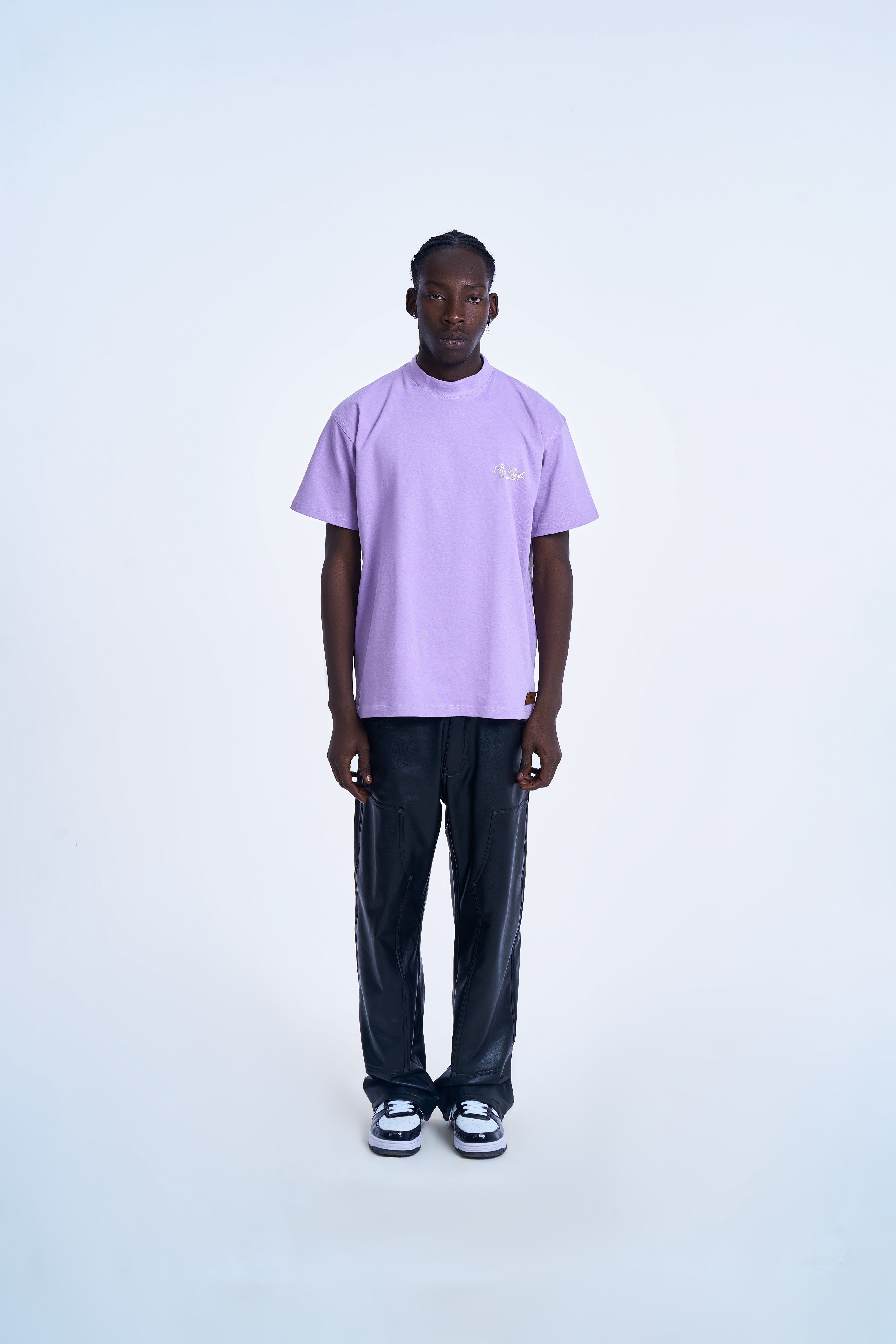 MOE CHARLIE Basic T-Shirt Lavendel Frontansicht – Script-Brustlogo, schwarze Lederhose, Air Jordan