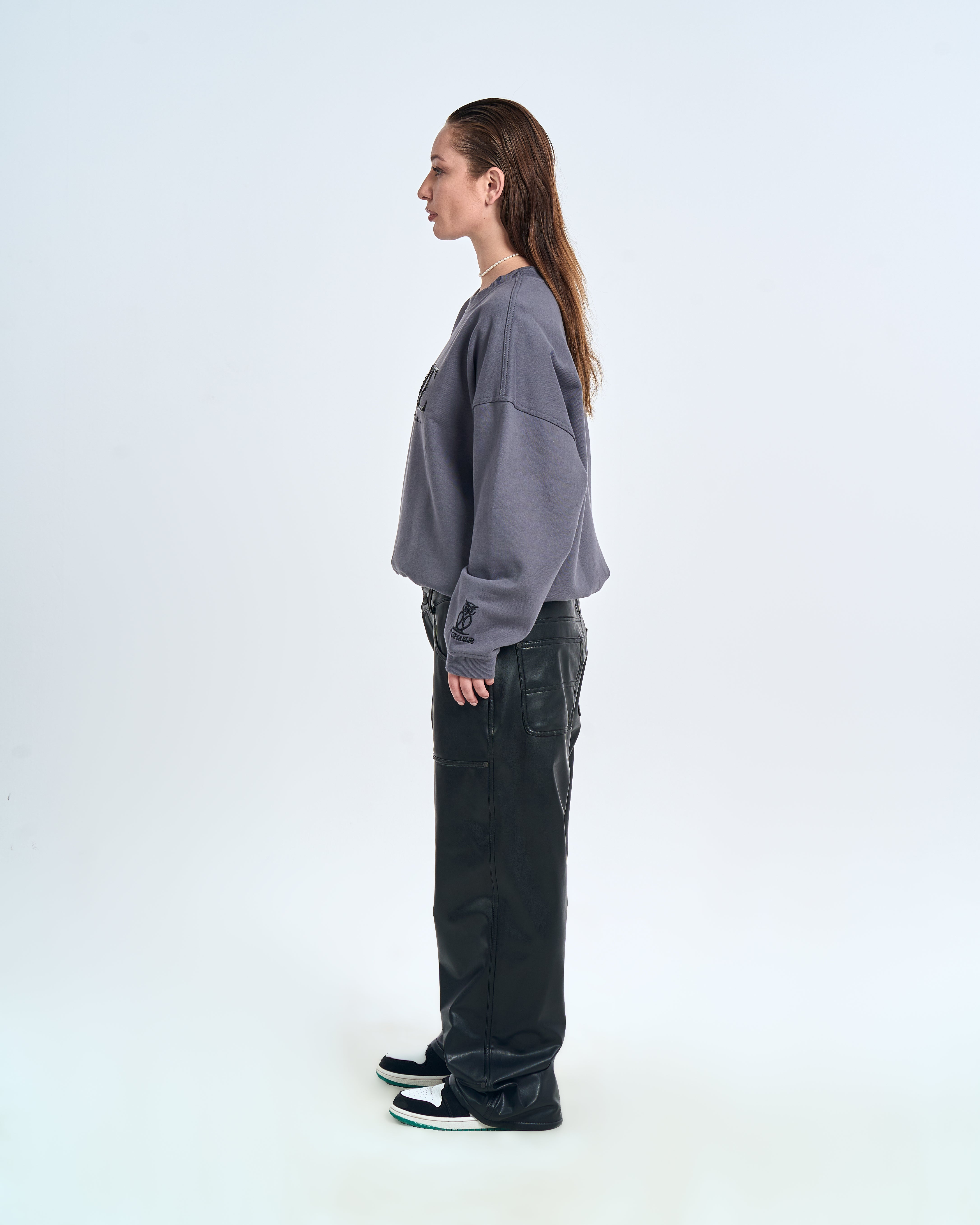 MOE CHARLIE Born in Exile Sweatshirt Grau, linke Seitenansicht weiblich, schwarze Lederhose, Perlenkette