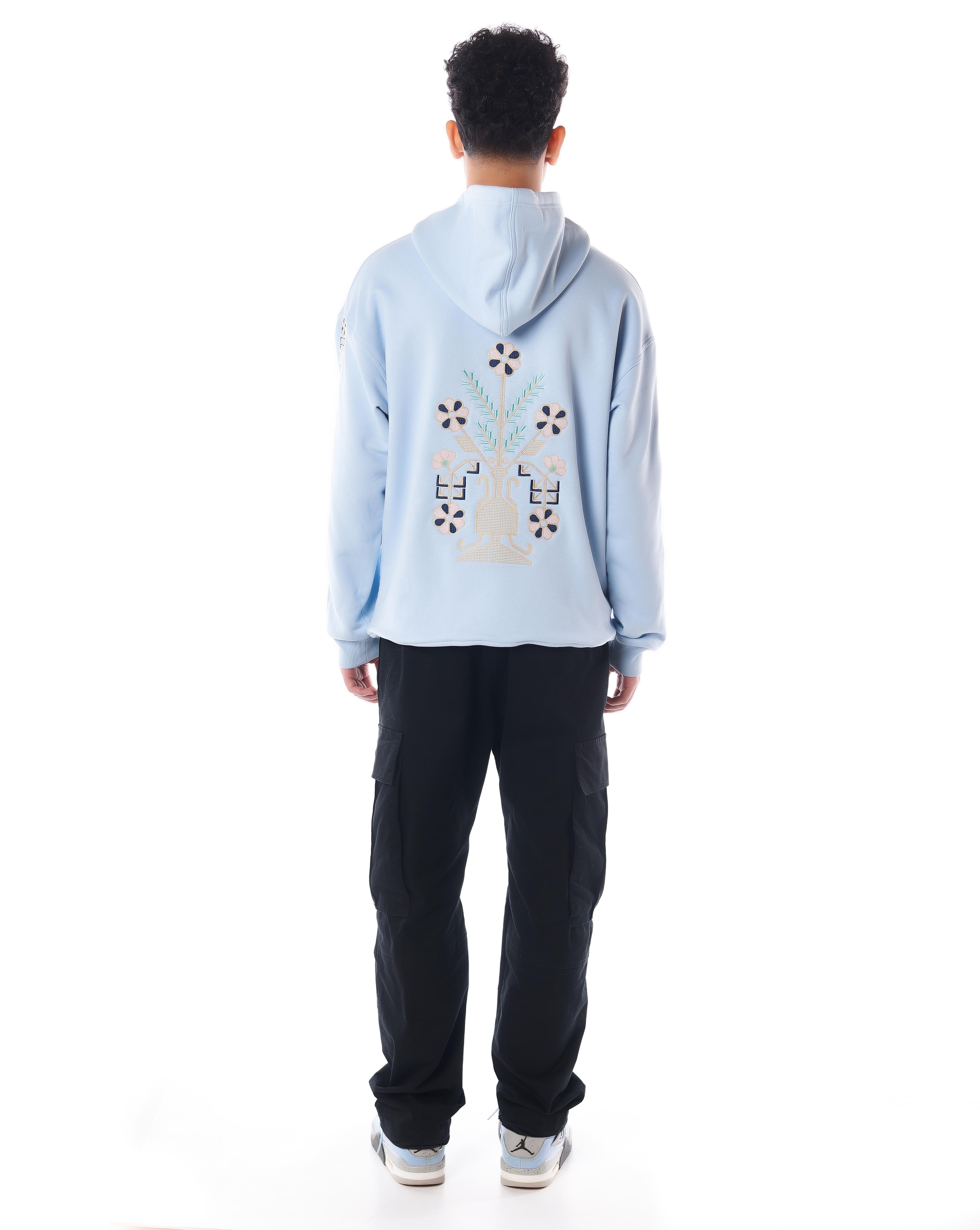 Rückenansicht The Culture Hoodie Hellblau, Fokus auf zentrale Blumenvase-Stickerei mit geometrischen Ornamenten