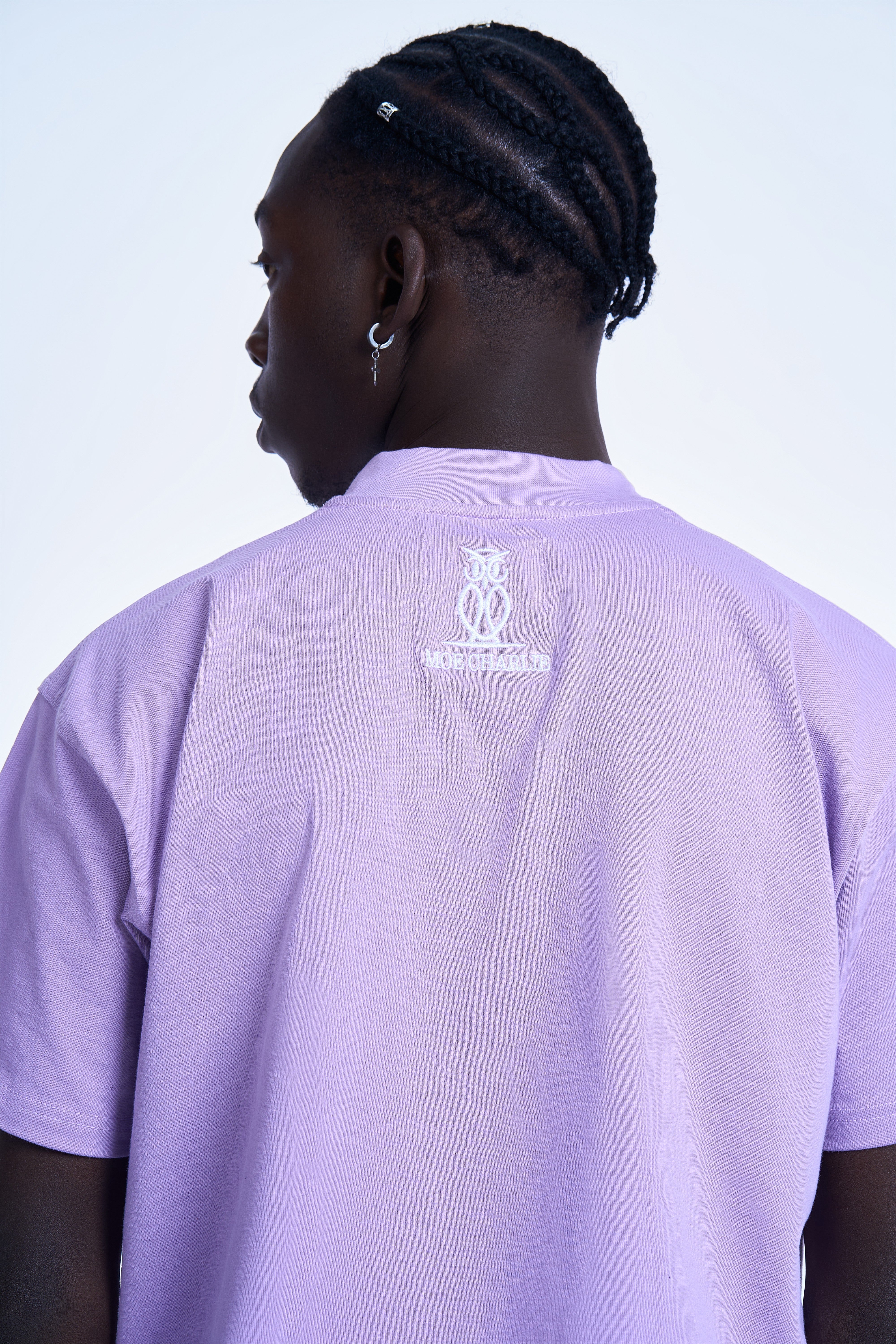Detailaufnahme Rücken-Stickerei MOE CHARLIE Basic Tee Lavendel – Eulen-Emblem mit Schriftzug in Weiß am oberen Rücken