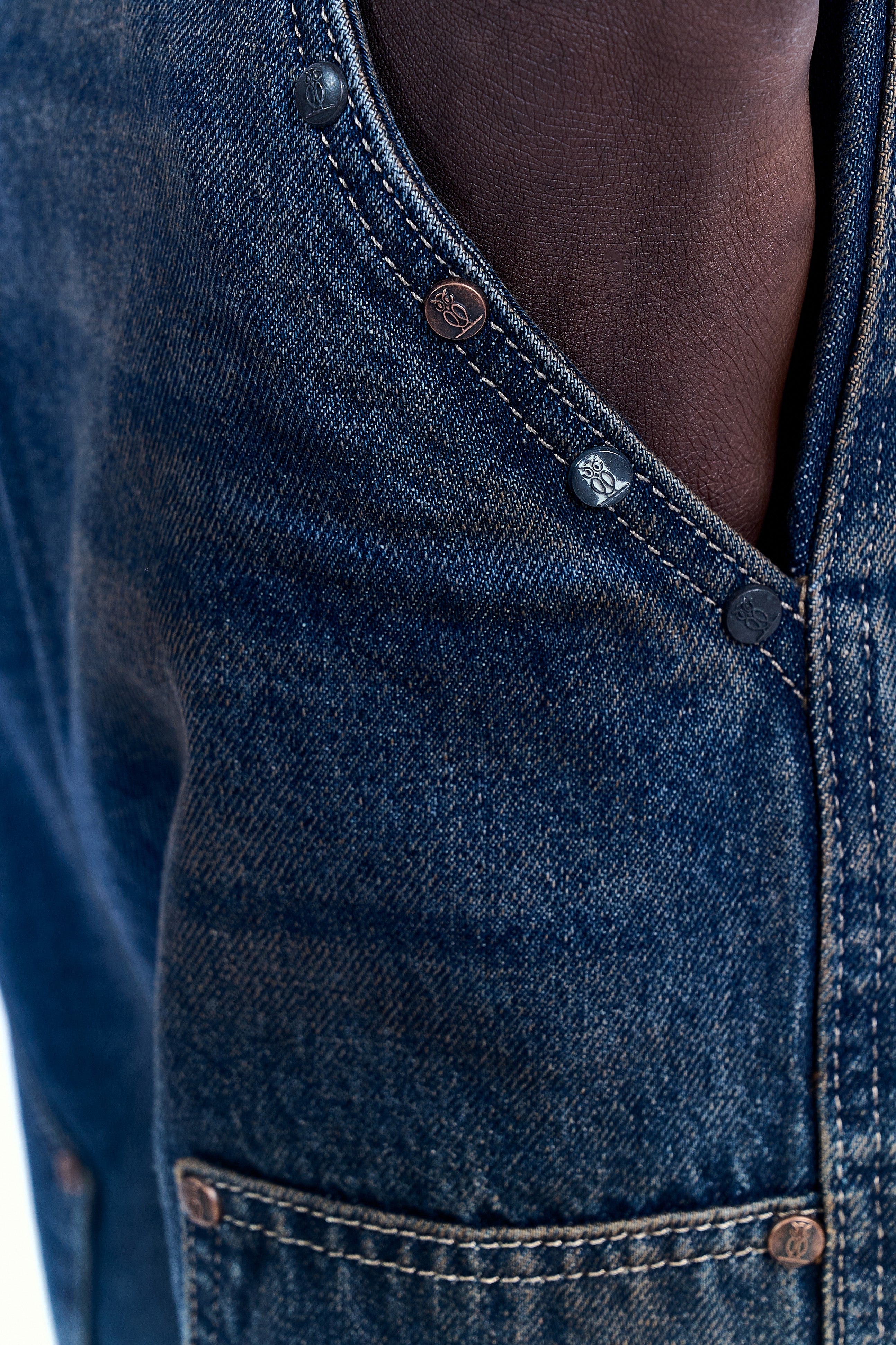 Nahaufnahme Hosenbund der MOE CHARLIE Double Knee Denim – Eulen-Emblem auf Druckknöpfen und Nieten in Kupferfarbe
