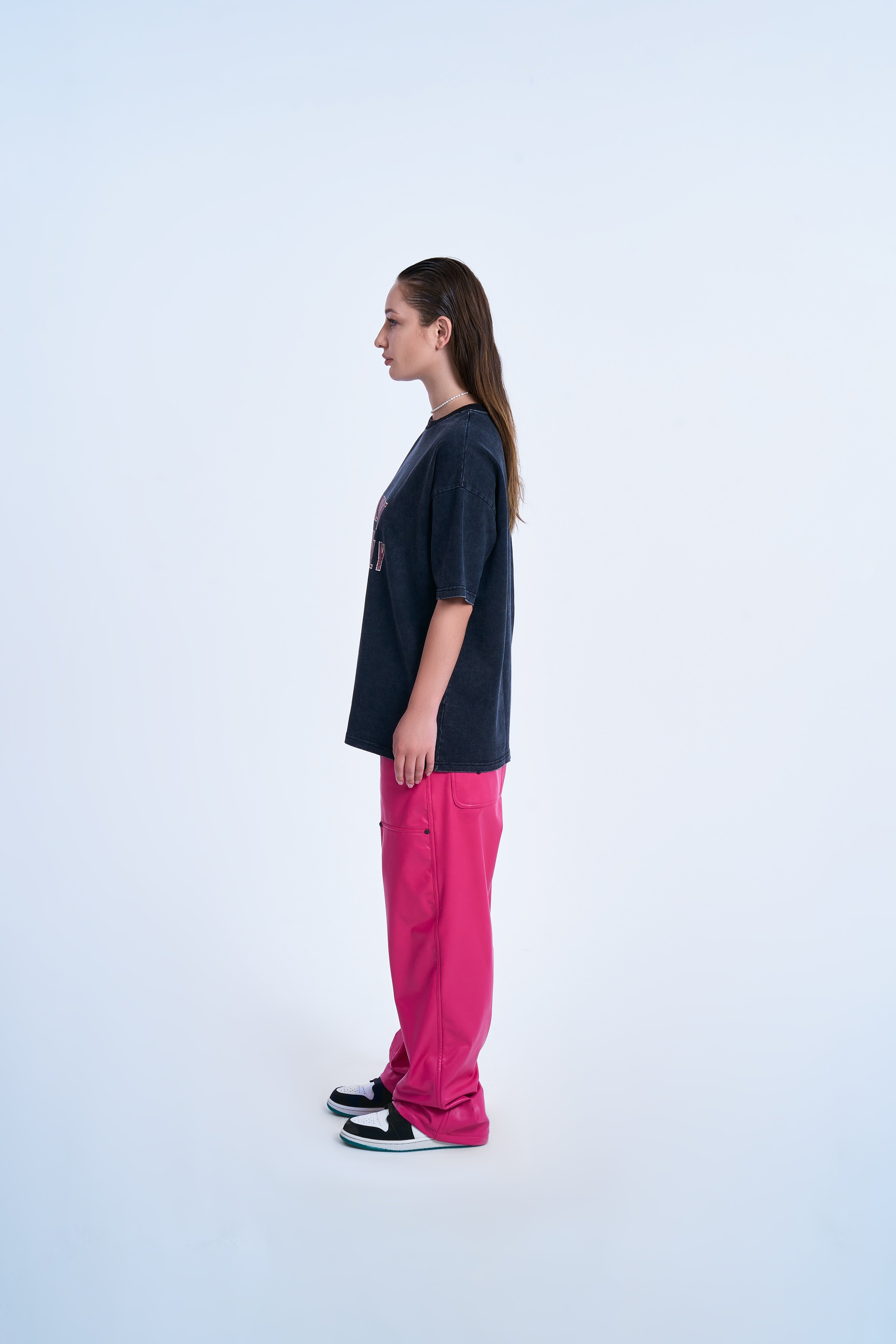 MOE CHARLIE Never Lonely T-Shirt – Seitenansicht links, Statement-Print seitlich sichtbar, pinkfarbene Lederhose
