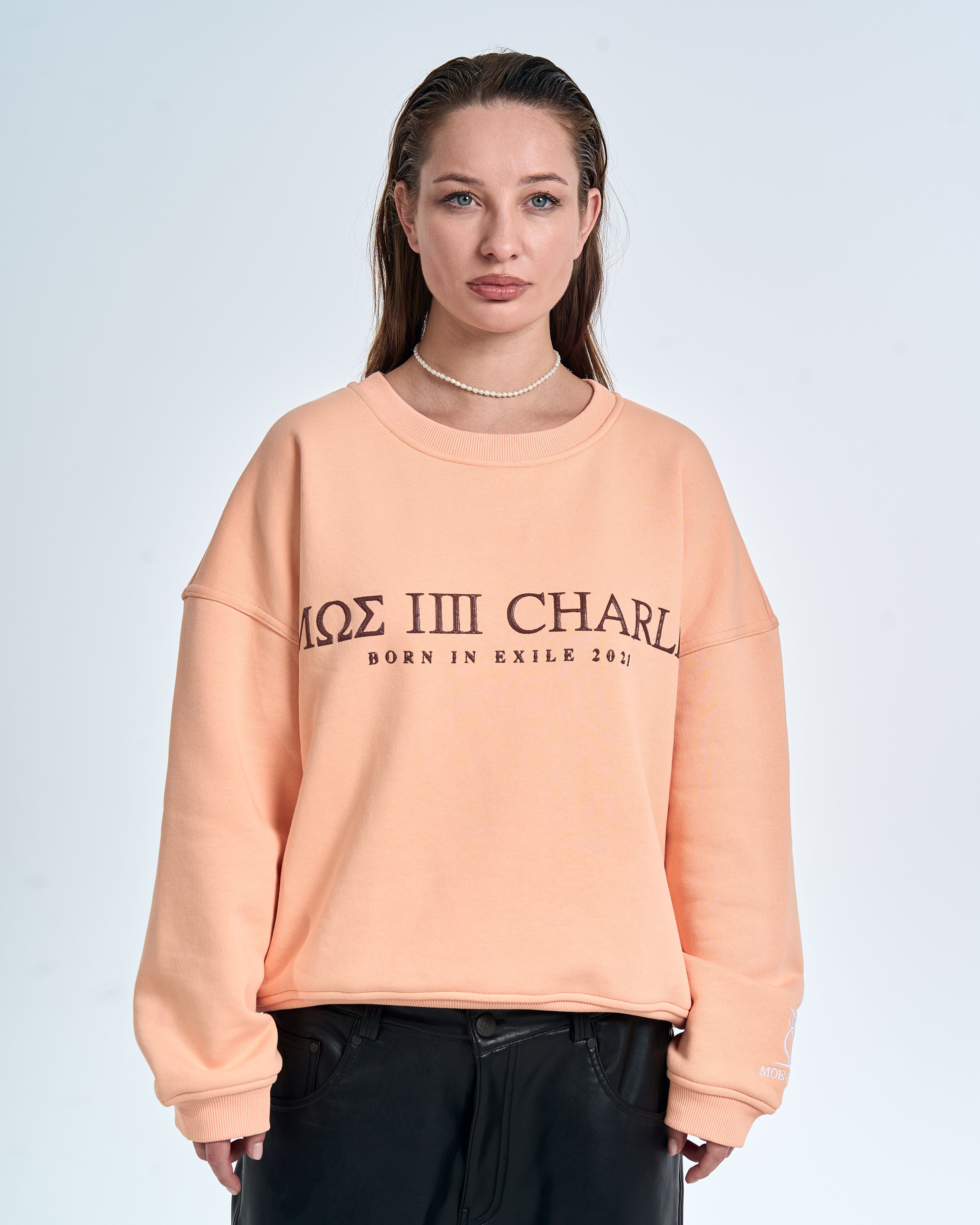 Nahaufnahme Frontprint Damen – MΩΣ IIII Charlie Born In Exile 2021 und Eulen-Logo am Ärmelcuff, Perlenkette