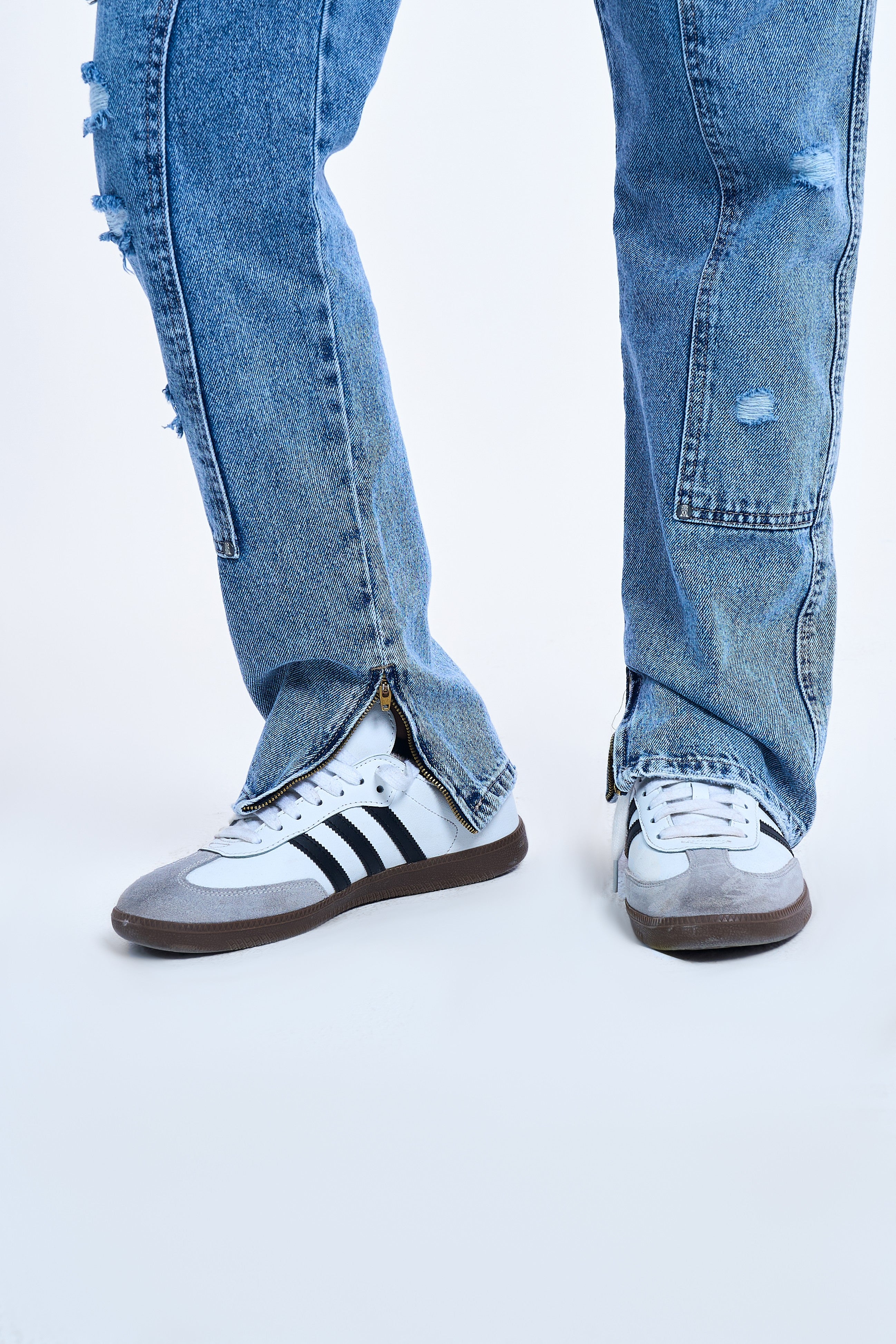 Saum-Detail der MOE CHARLIE Carpenter Flare Denim – Knöchel-Zipper geöffnet, kombiniert mit Adidas Samba Sneakers