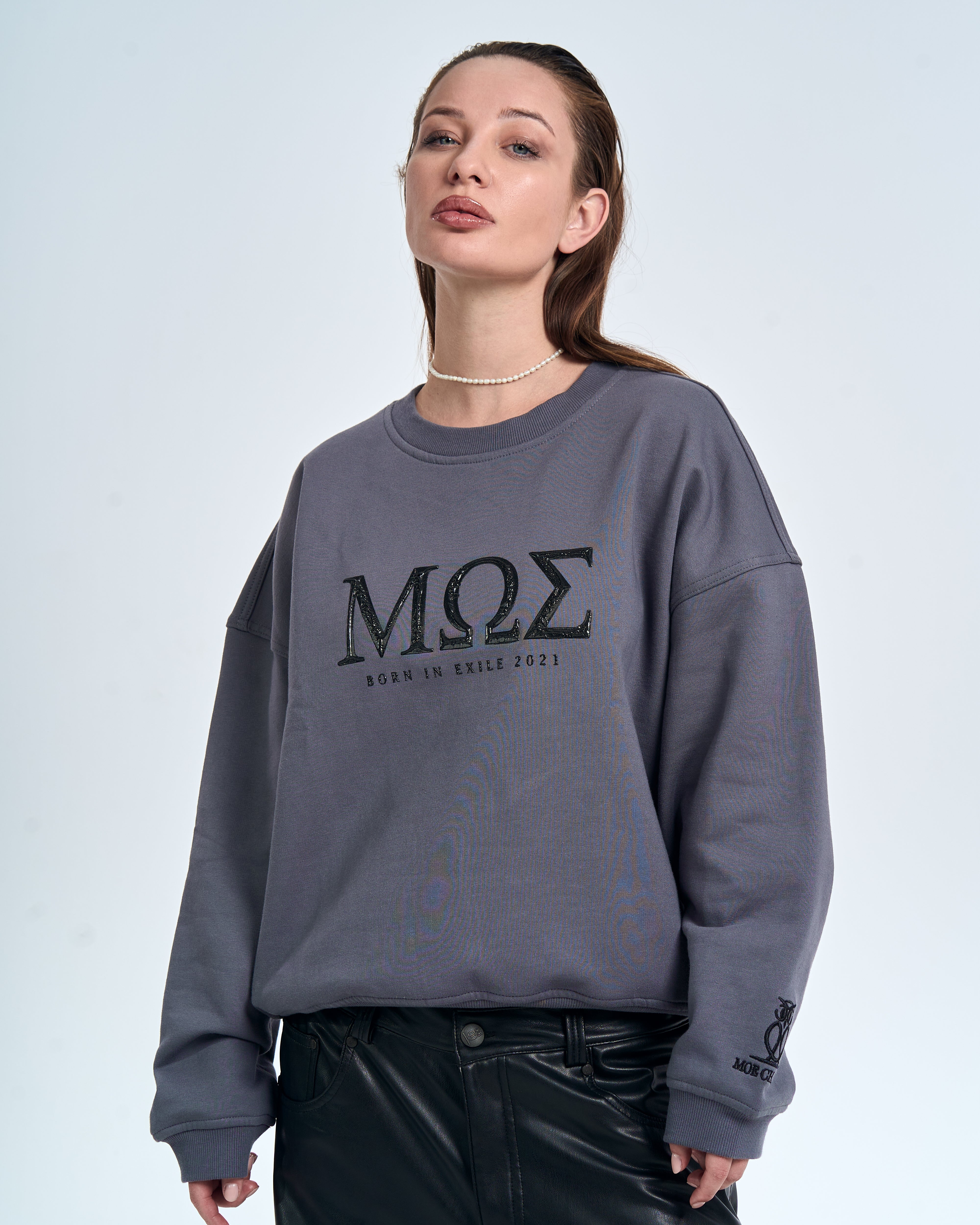 Nahaufnahme MOE CHARLIE Born in Exile Sweatshirt Grau – MΩΣ-Frontprint in Glanzoptik, seitlicher Blick