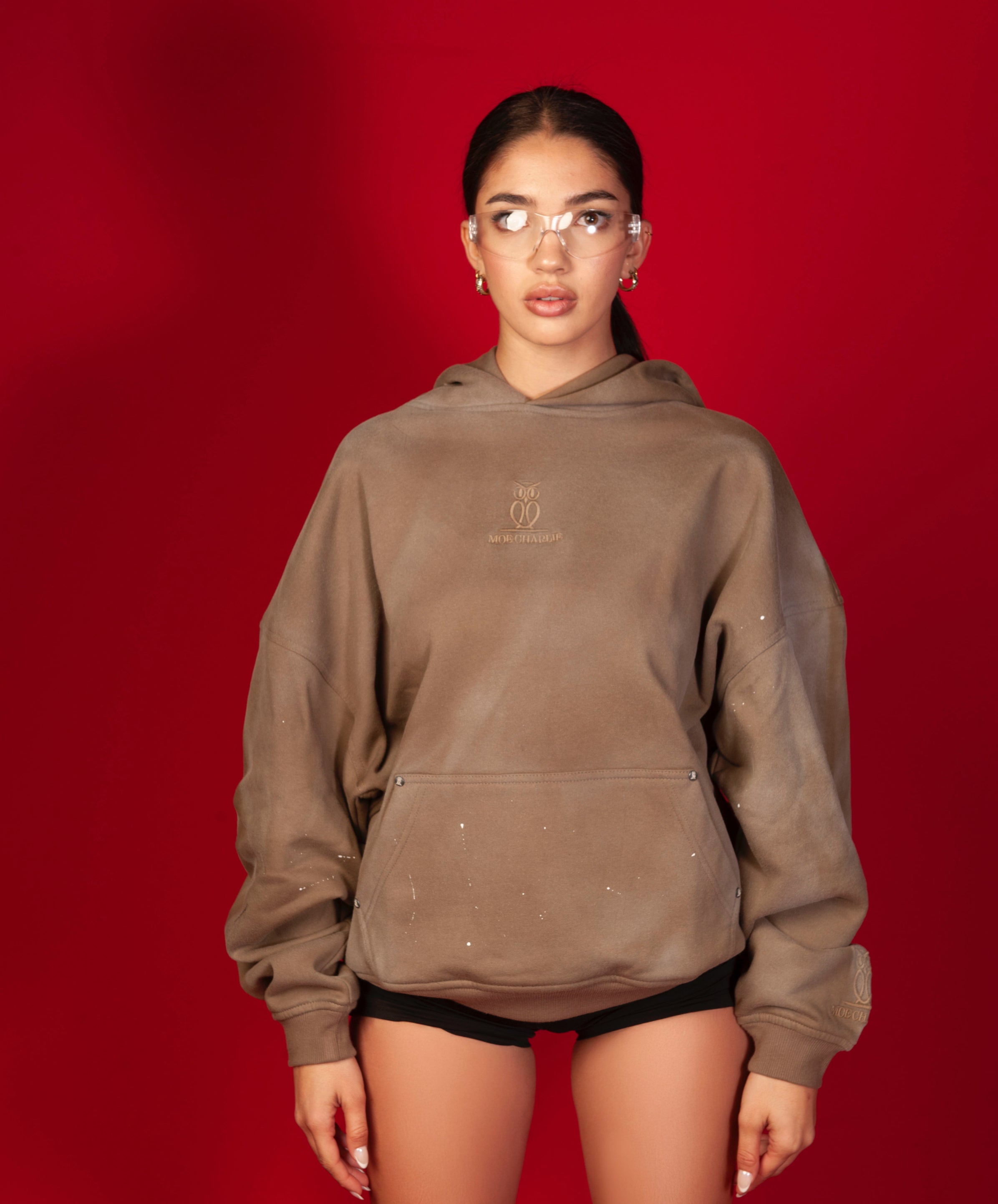 MOE CHARLIE Artist Hoodie Frontansicht weiblich, taupefarbener Hoodie mit tonal gesticktem Logo, Kanguru-Tasche
