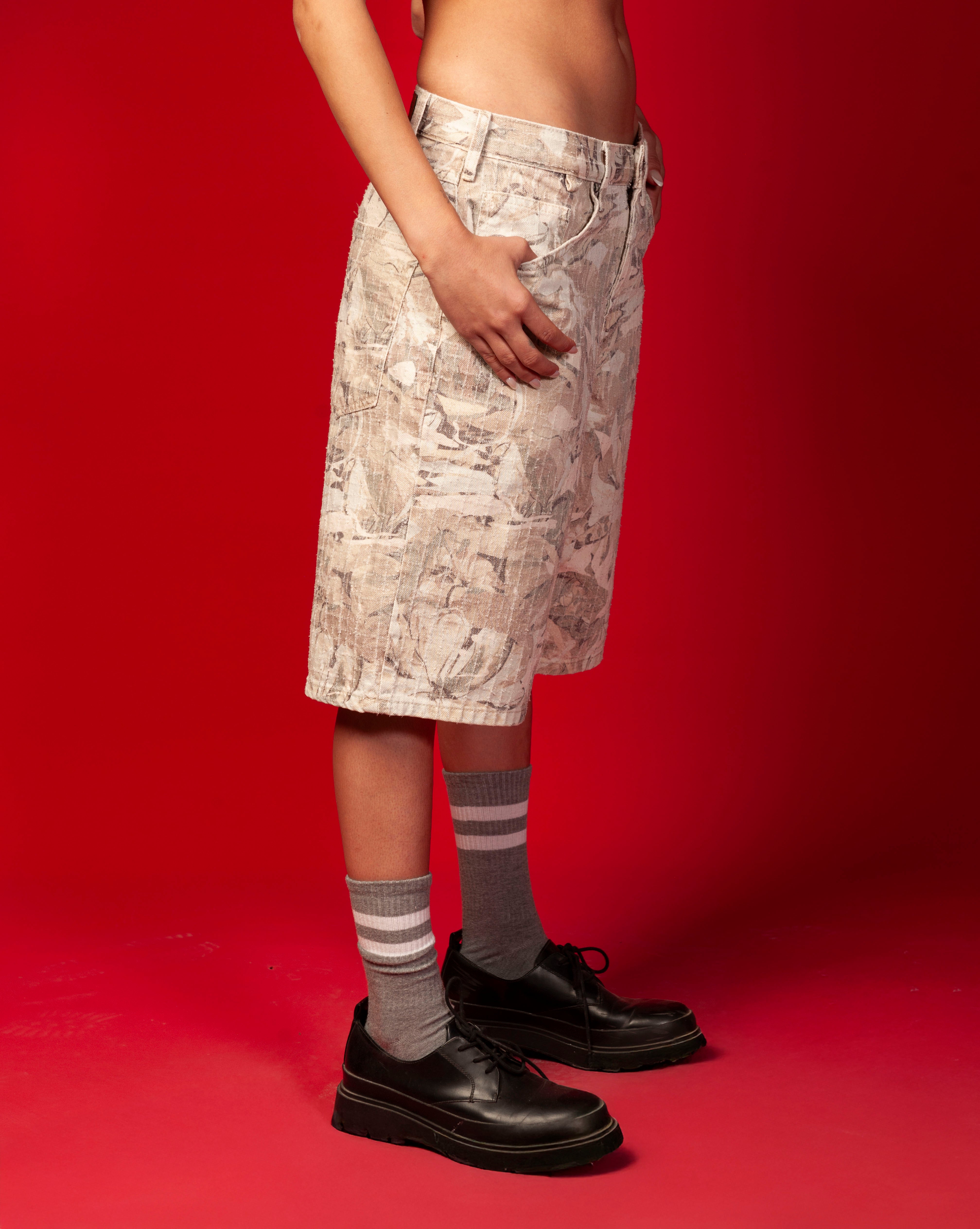 MOE CHARLIE Baggy Jorts, zweite Seitenansicht weiblich - Hand an Seitentasche, Streifensocken sichtbar
