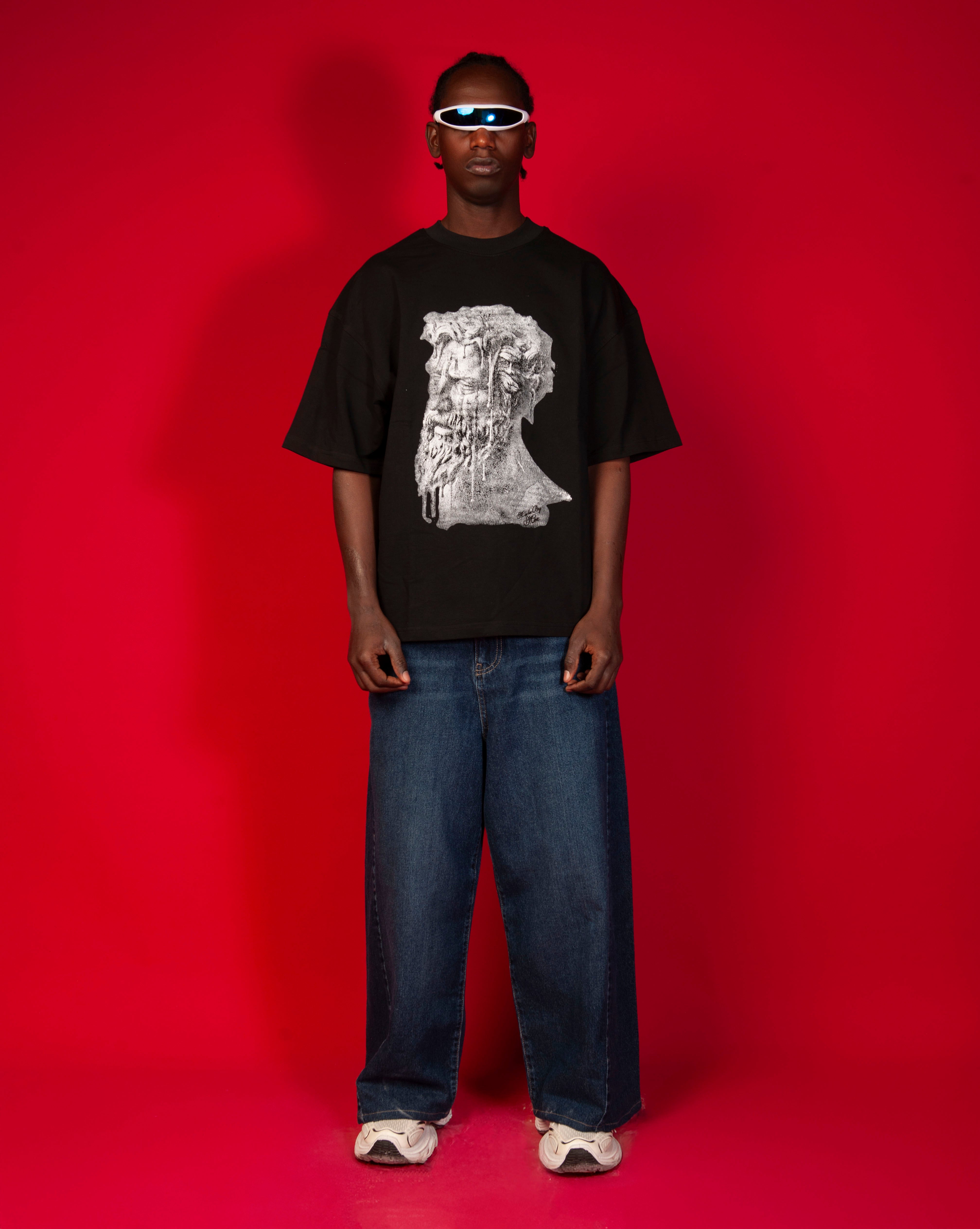 Patience T-Shirt MOE CHARLIE Frontansicht Ganzkoerper, schwarzes Tee mit Buesten-Print, weisse Sneakers und Visor-Brille