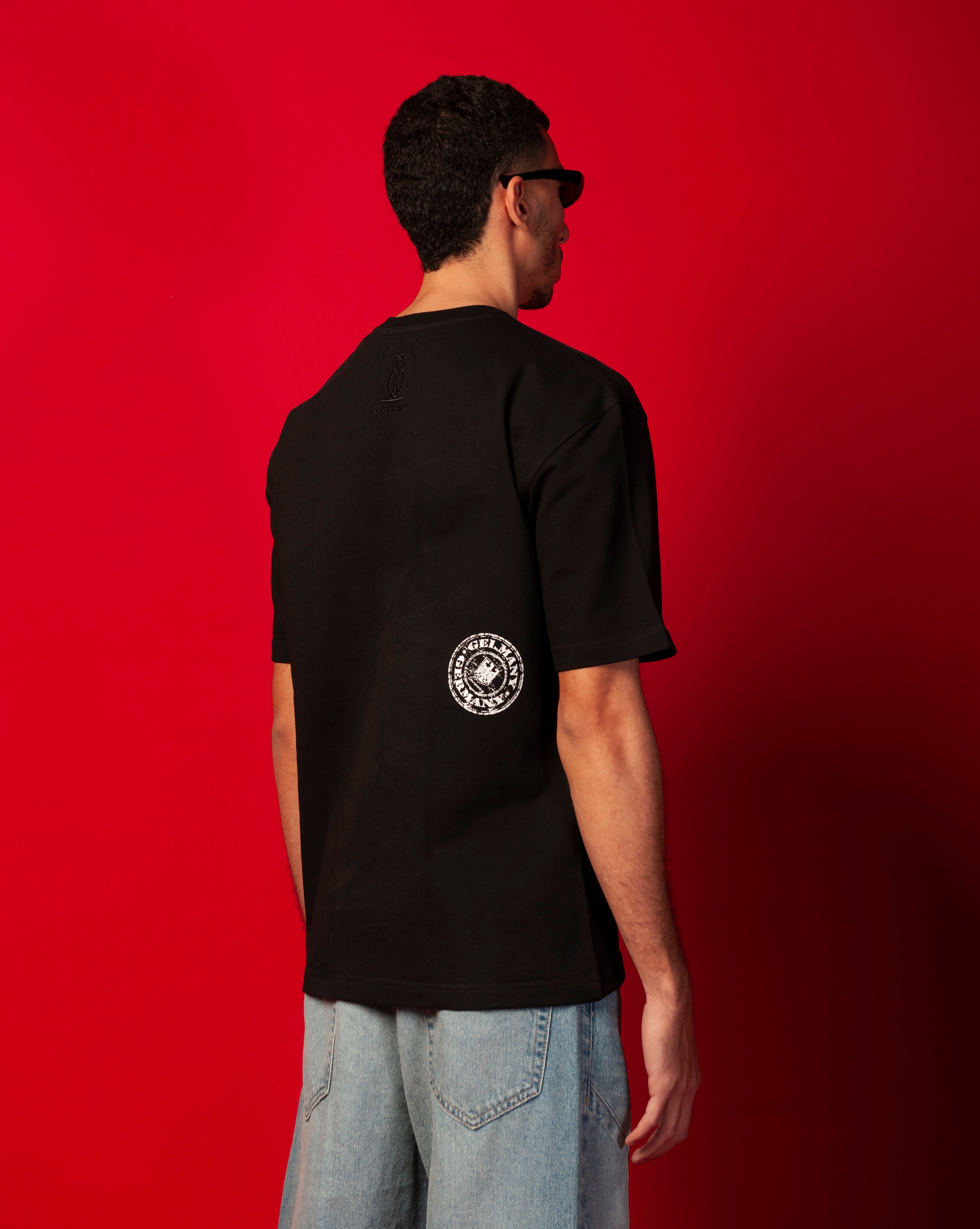 Rueckenansicht Stampel T-Shirt MOE CHARLIE, weisser Stempelprint auf Rueckenpartie, maennlich mit Brille