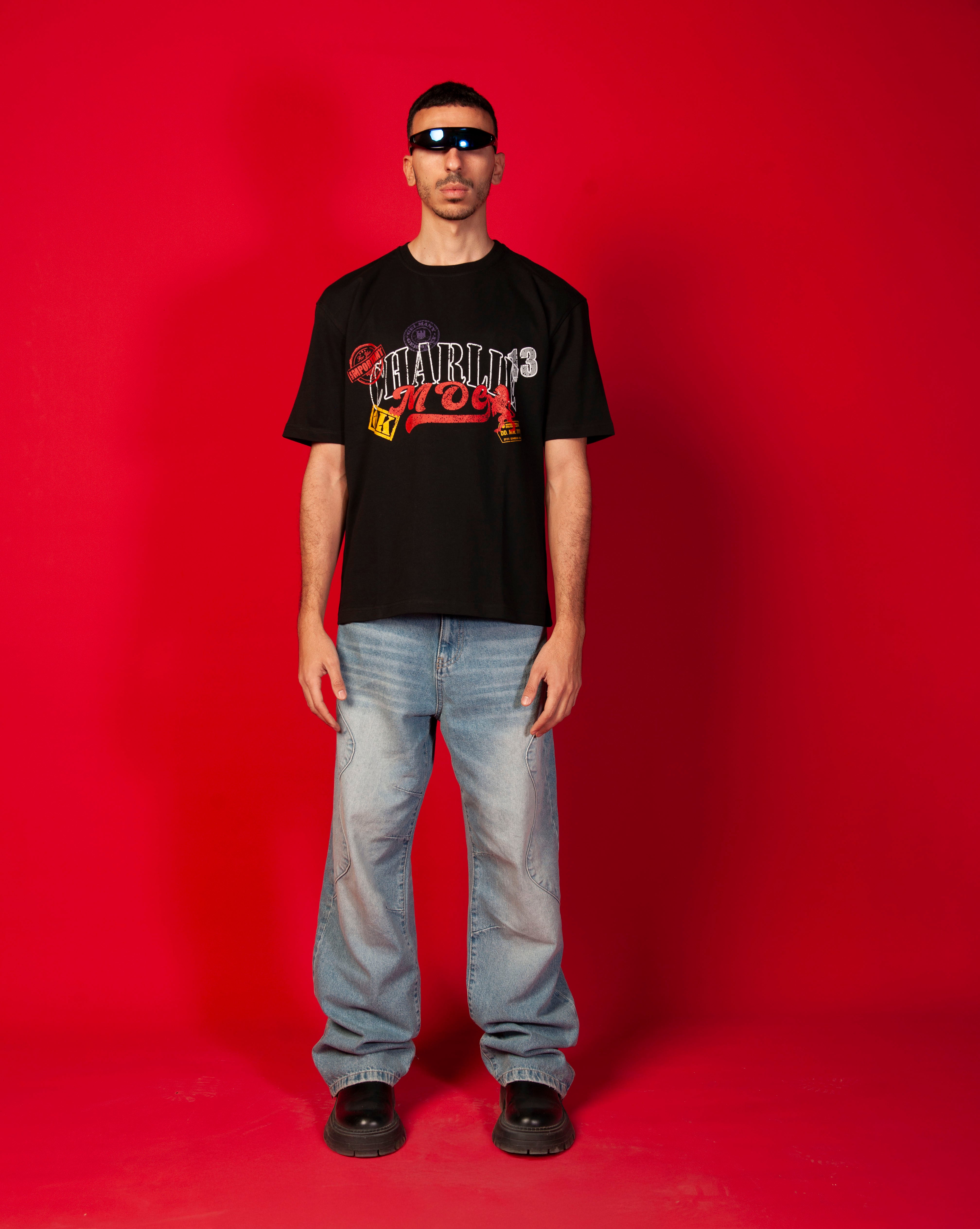 Stampel T-Shirt MOE CHARLIE, Frontansicht maennlich Ganzkoerper, schwarzes Tee, Stempel-Print, Jeans und schwarze Boots