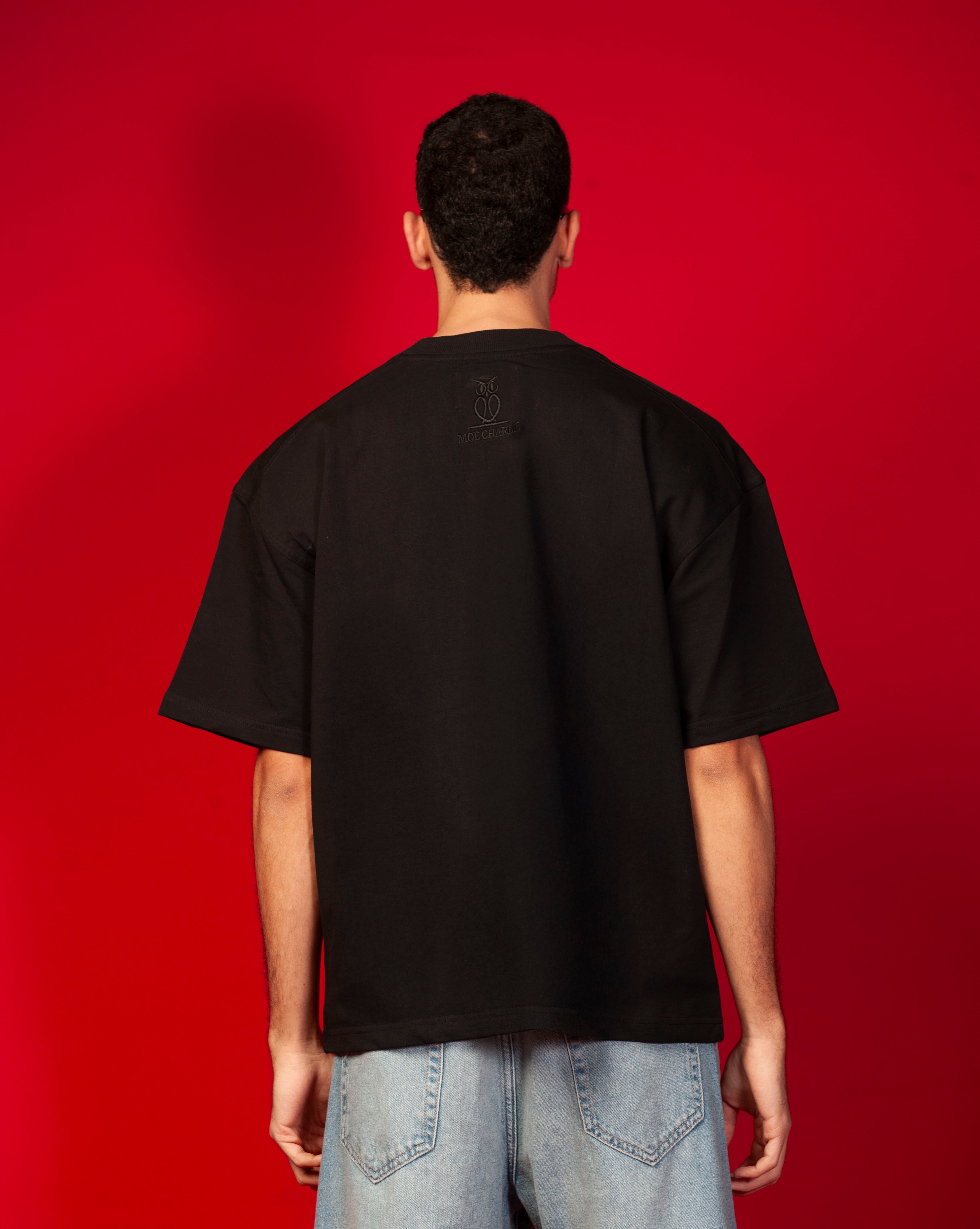Rueckenansicht Genius T-Shirt MOE CHARLIE, schwarze saubere Rueckseite mit tonal schwarzem MOE CHARLIE Owl-Logo oben