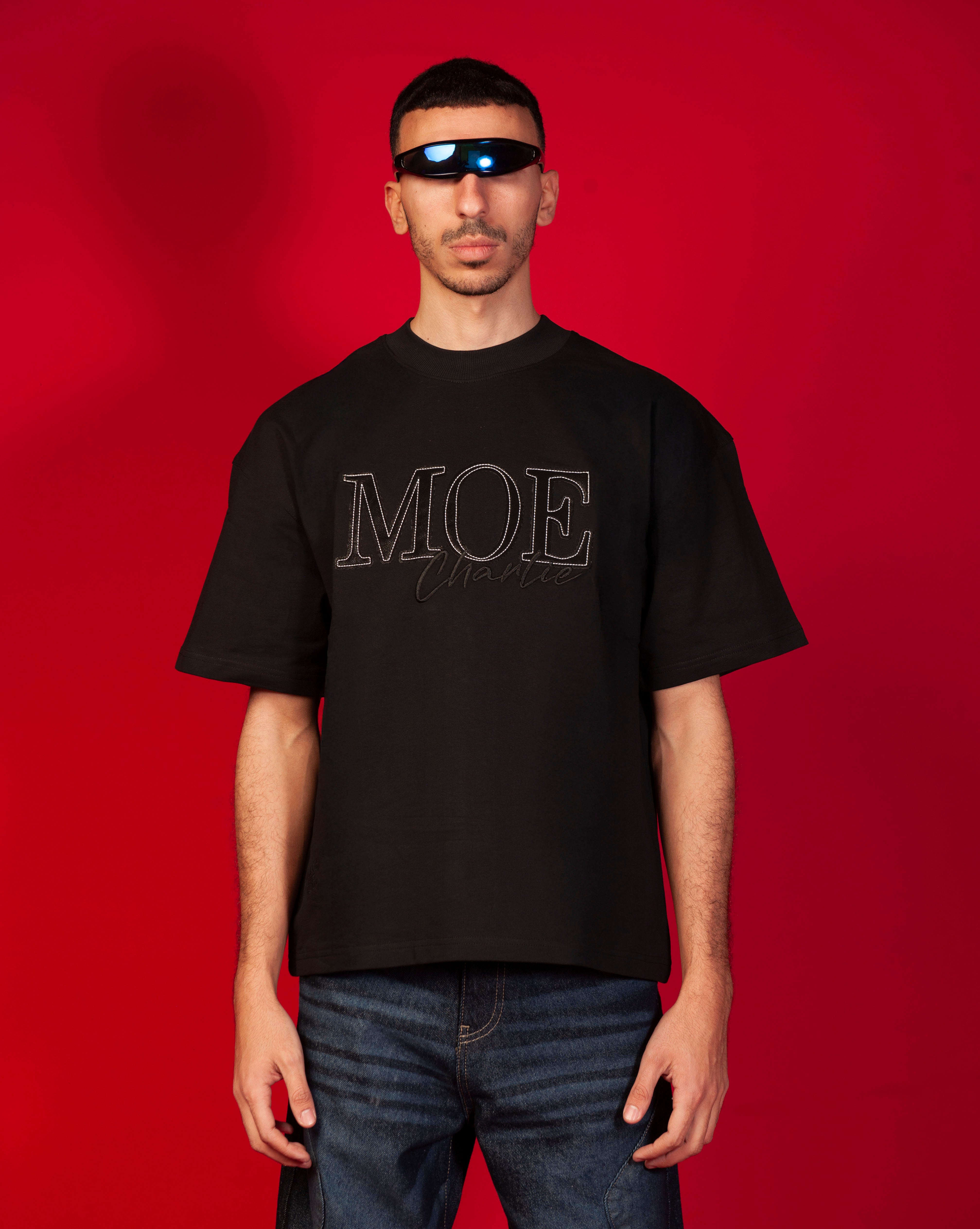MOE CHARLIE MOE Oversize T-Shirt Frontansicht, schwarzes Tee mit grossem tonalen MOE-Charlie-Stick, Visor-Brille
