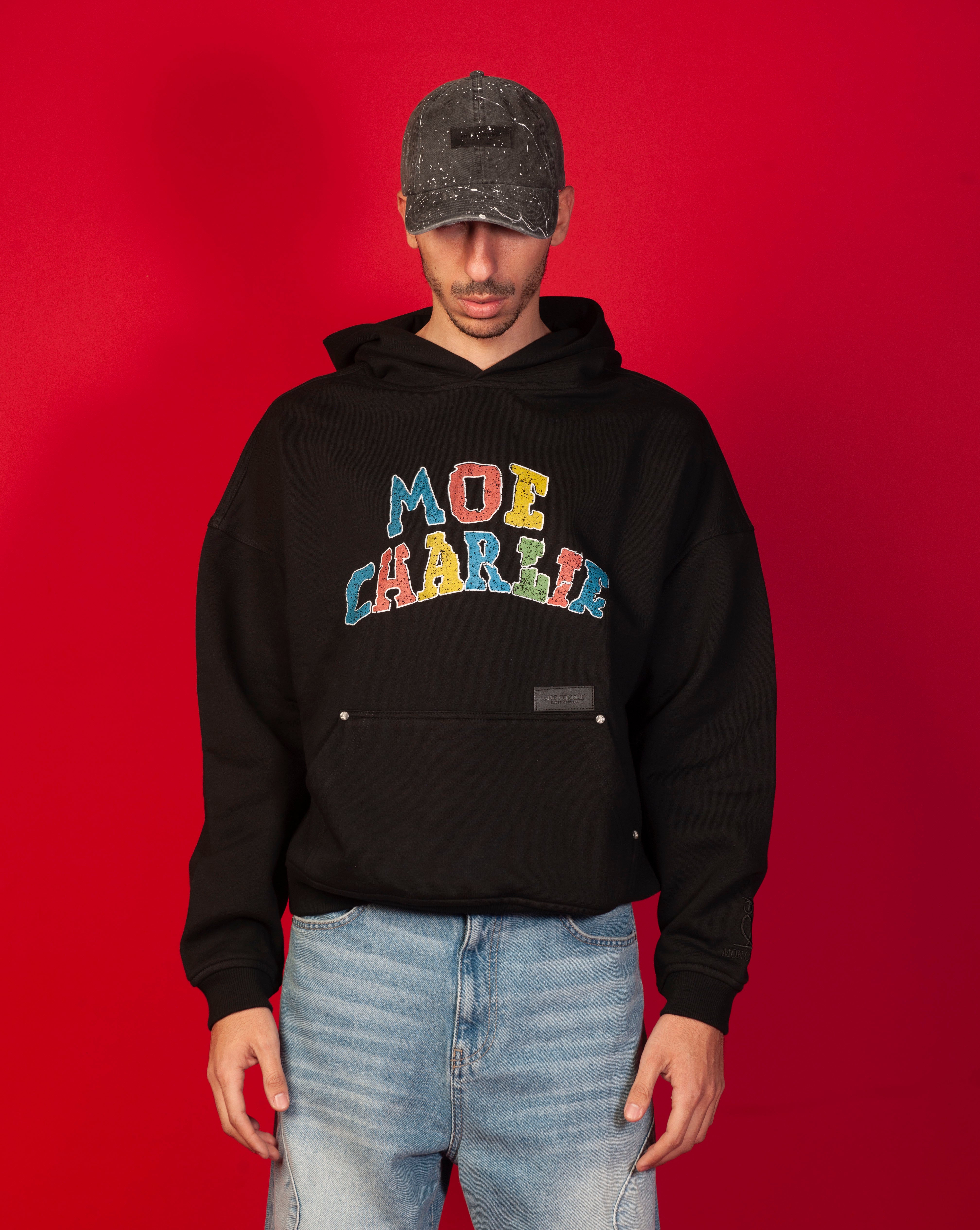 Google Hoodie MOE CHARLIE, Frontansicht maennlich, bunter Collegiate-Print, Destroyed-Cap und helle Jeans